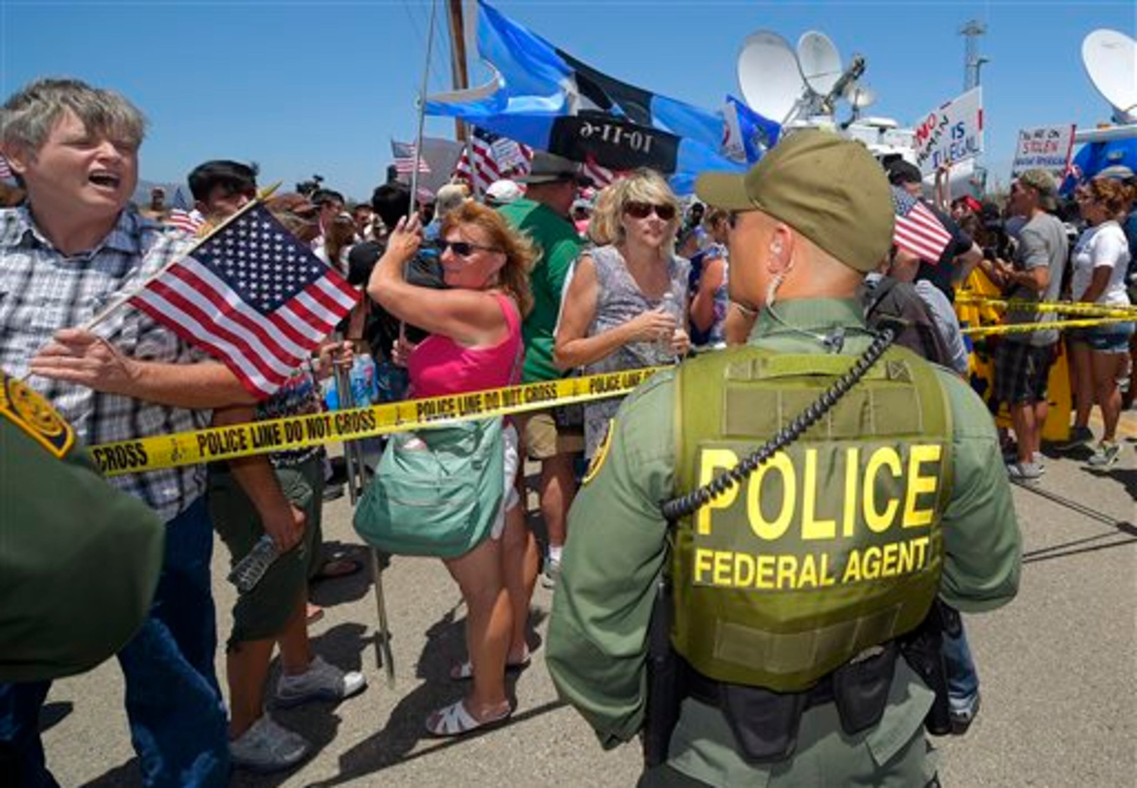 Demonstrators yell to a U.S. Customs and Border Protection officer, Friday, July 4, 2014, outside a U.S. Border Patrol station in Murrieta, Calif. Demonstrators on both sides of the immigration debate had gathered where the agency was foiled earlier this week in an attempt to bus in and process some of the immigrants who have flooded the Texas border with Mexico. (AP Photo/Mark J. Terrill)