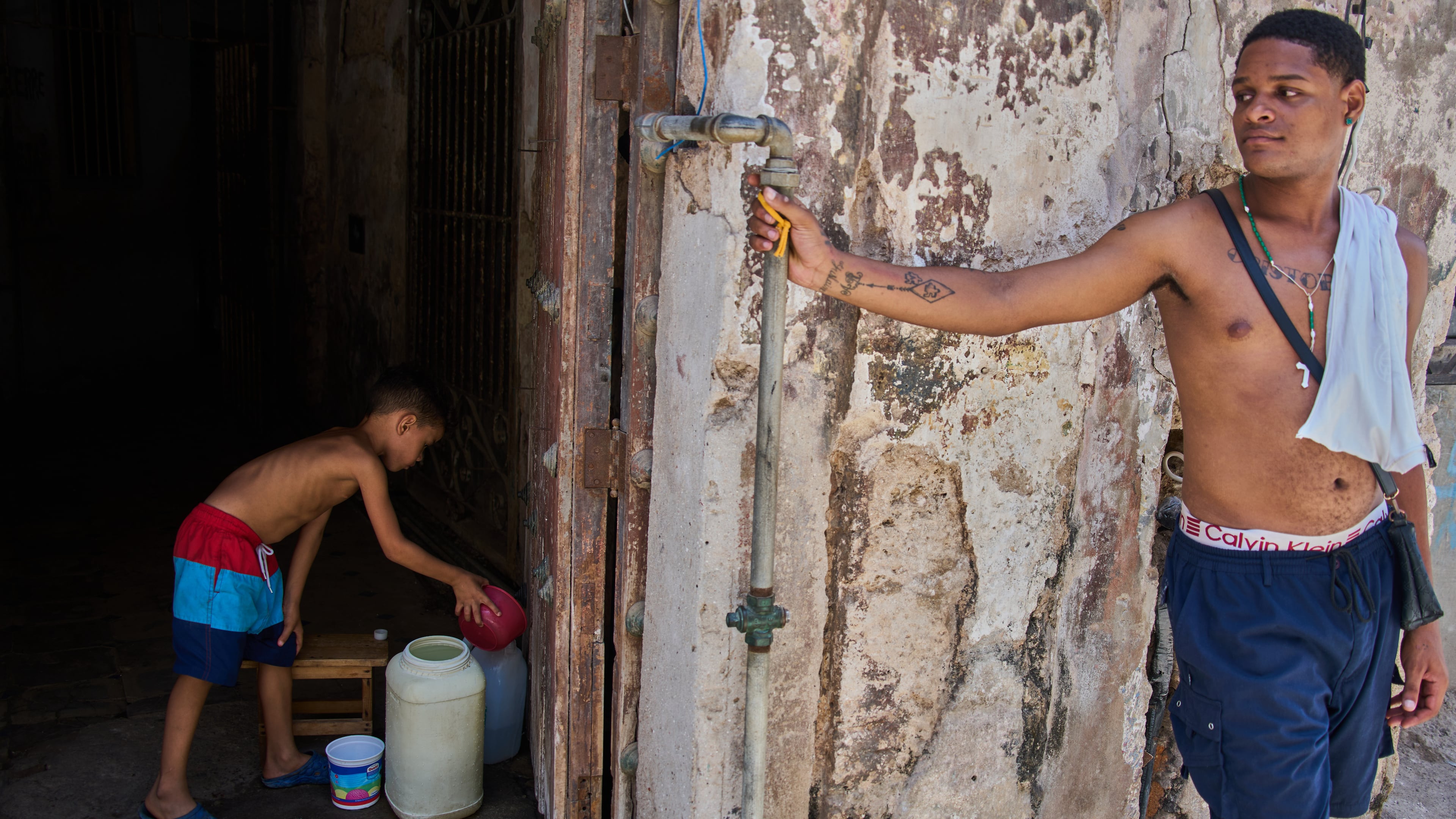 A youth collects water from the bottom floor of a residential building, during a blackout that stopped the water pump, in Havana, Cuba, Tuesday, July 14, 2026. (AP Photo/Ramon Espinosa)