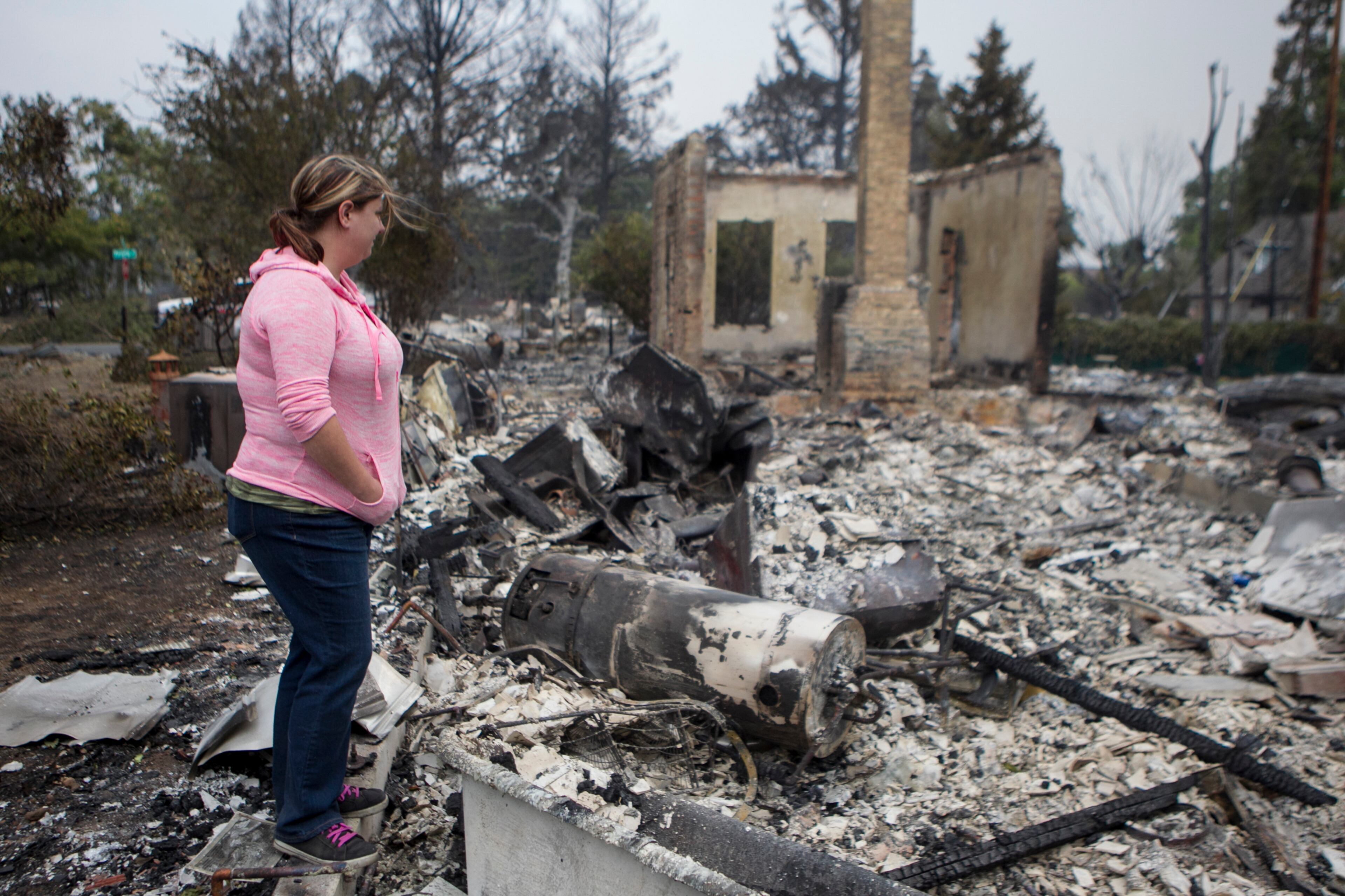 Deanna Hingst looks over what remains of her home after it was burned by a wildfire in Middletown, Calif., Sept. 14, 2015. Despite the efforts of thousands of firefighters, three major fires have consumed 270,000 acres, forcing the evacuation of thousands of people, state officials said. (Ilana Panich-Linsman/The New York Times)
