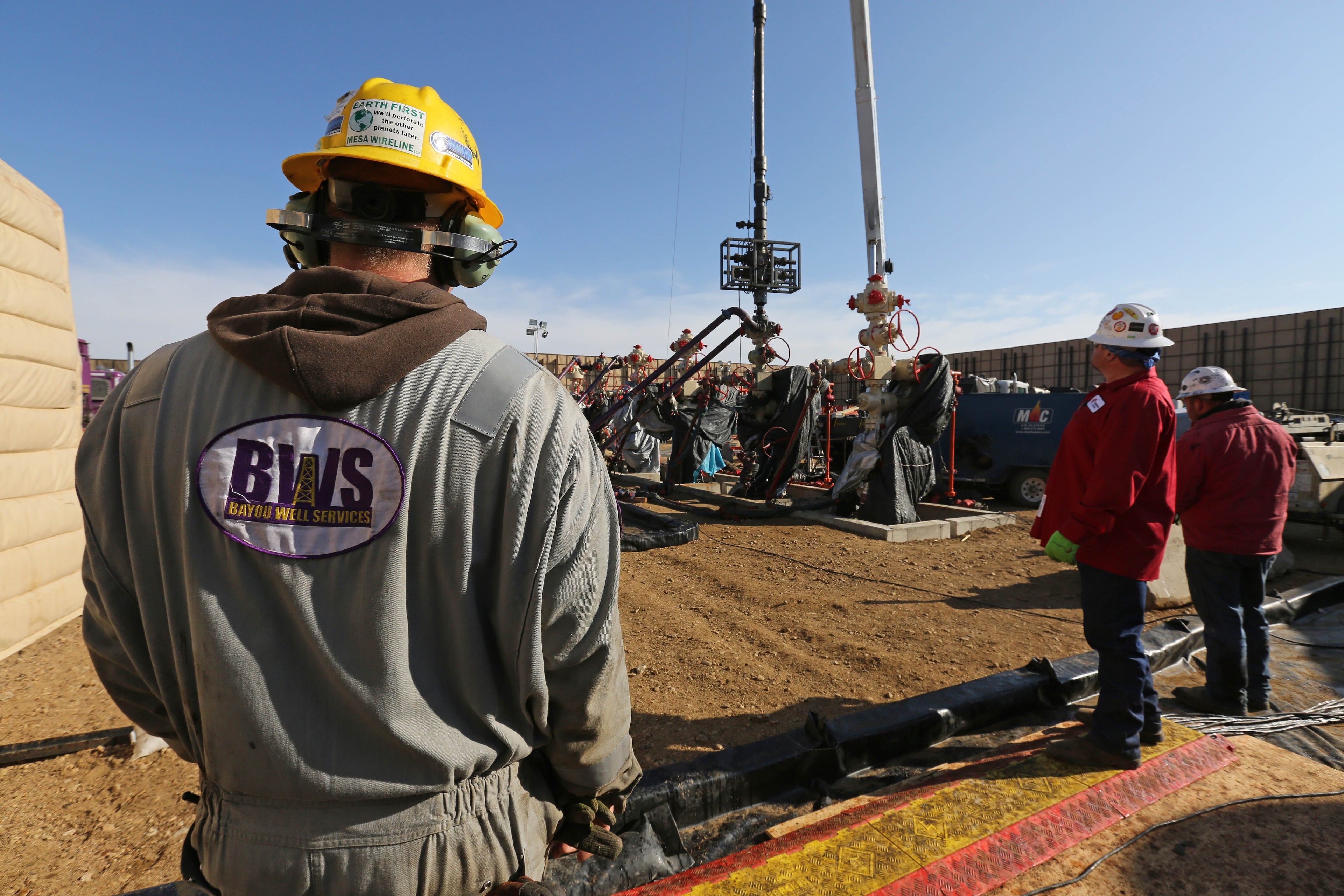 In this March 25, 2014 photo, workers keep an eye on well heads during a fracking operation, near Mead, Colo. (AP Photo/Brennan Linsley)