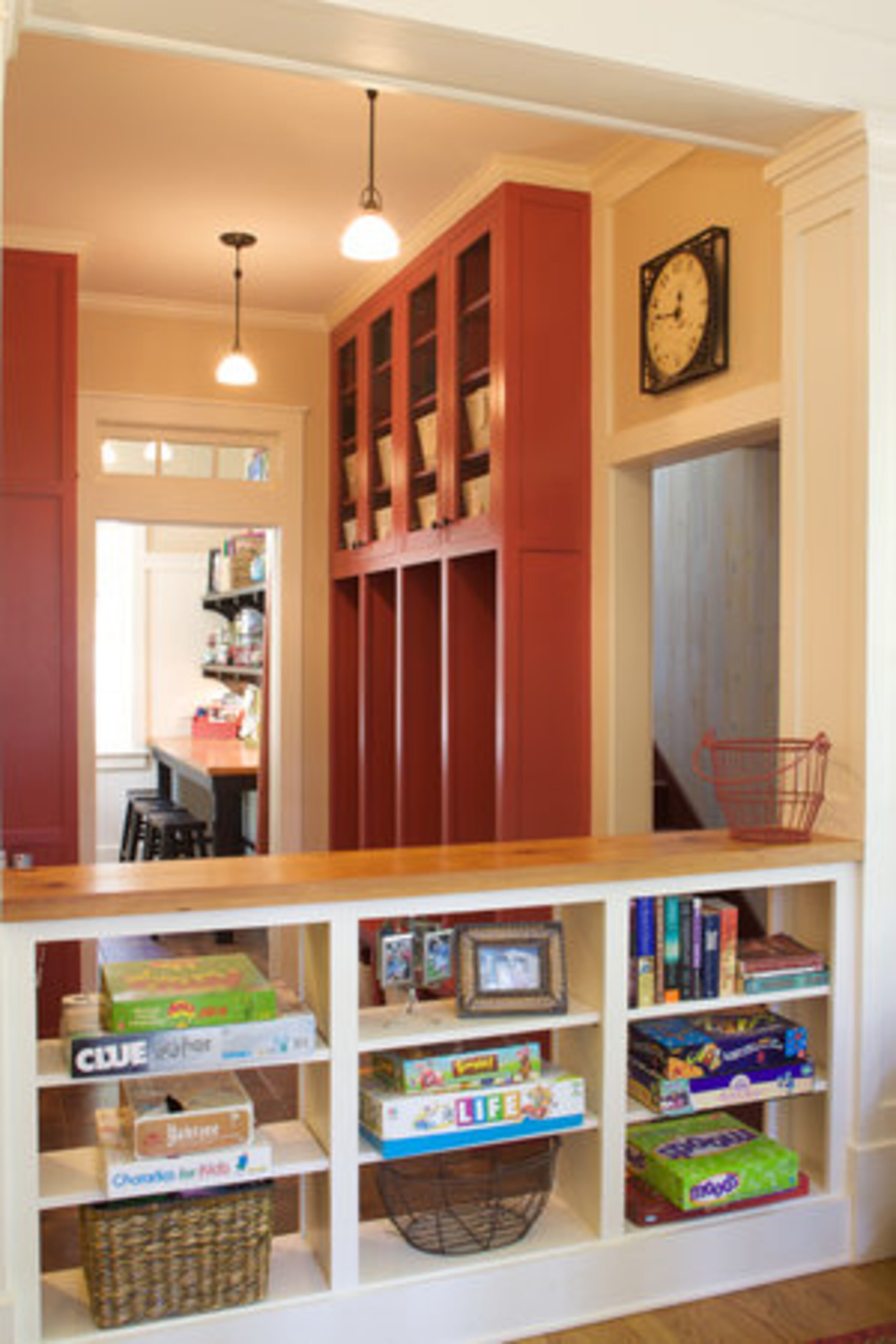 The half bookcase was designed to create two separate spaces between the mudroom and the sunroom while allowing the area to remain open. The large red lockers are each assigned to a member of the family for storing backpacks and coats.