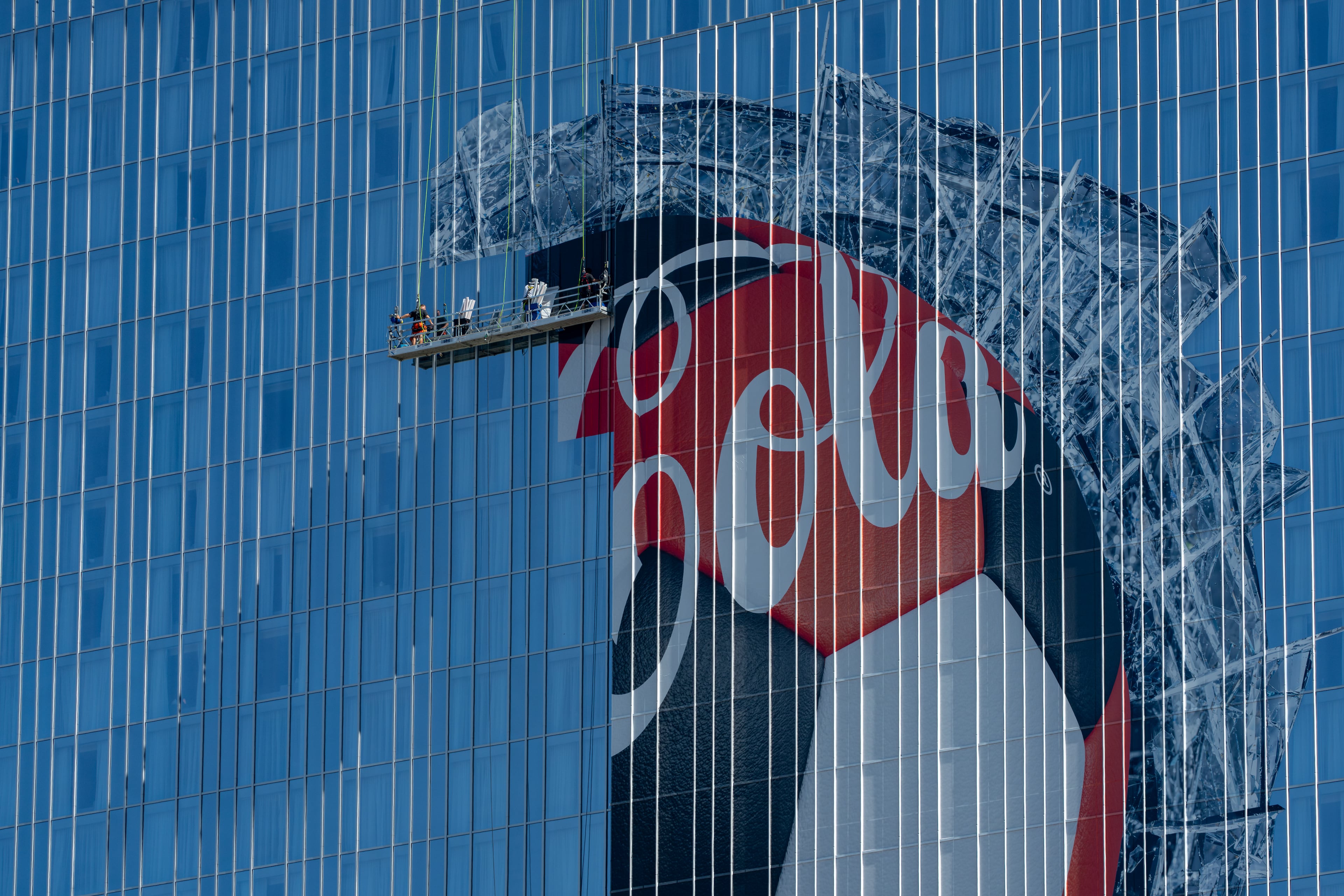 Workers apply a Coca-Cola advertisement to the side of the Signia hotel on Thursday, June 4, 2026. (Ben Hendren for the AJC)
