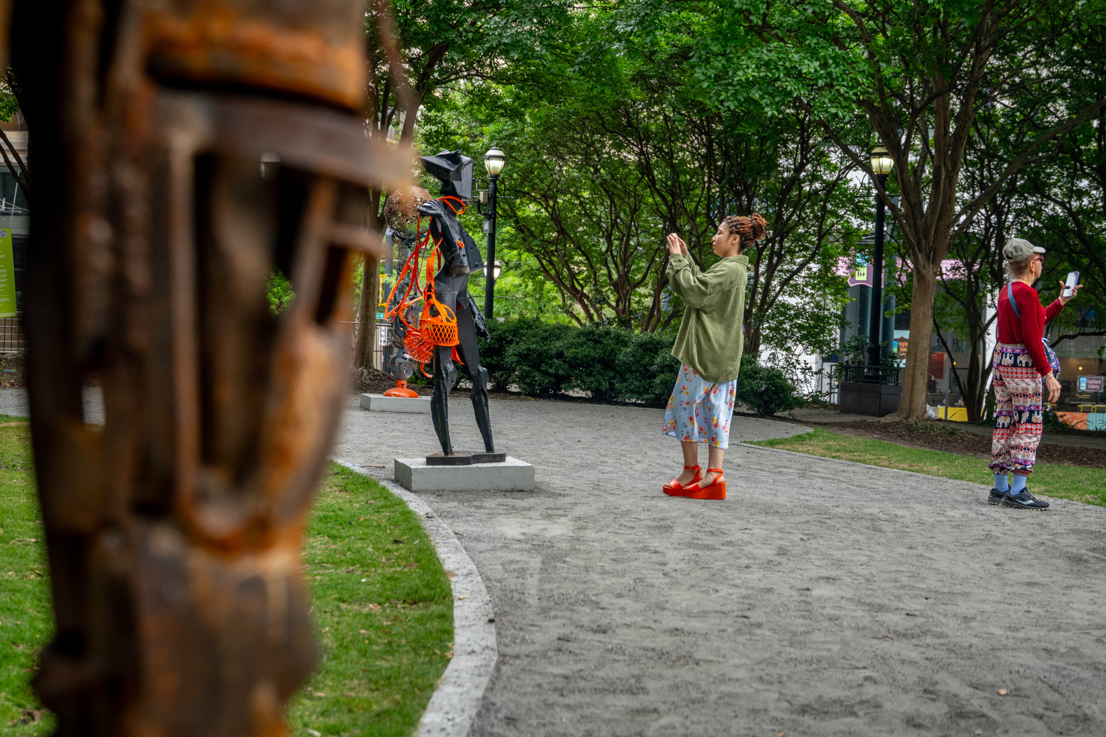Visitors admire the sculptures of Olu Amoda, an Alpharetta-based Nigerian artist who is currently featured in Woodruff Park as part of the Art in the Park series. (Jeffrey Moustache/AJC)