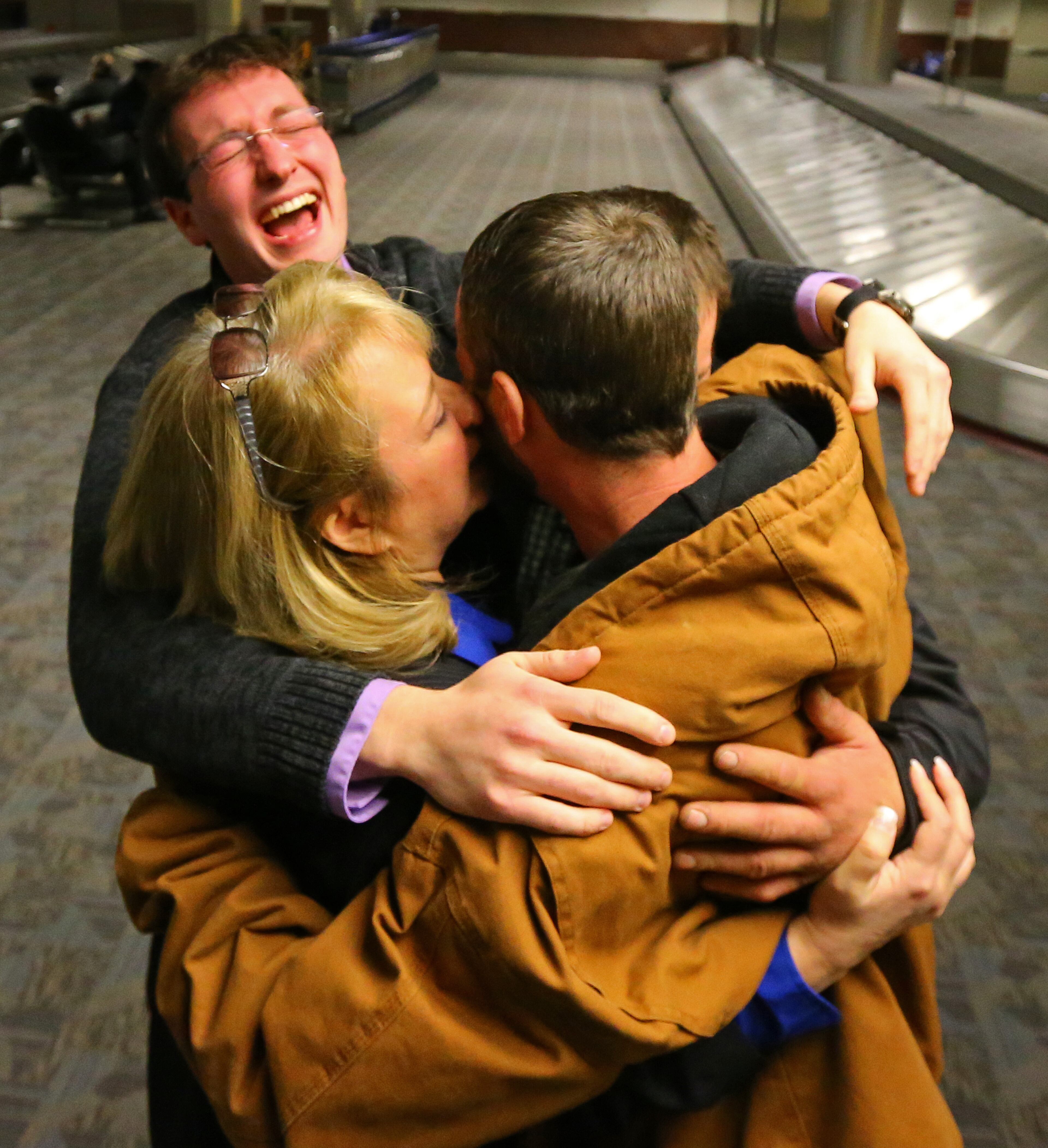 112813 ATLANTA: Stepmother Deanna Rodecki (from left) and his brothers Andrew Rodecki and Erick Hordos smother Joel Hartman, the homeless man who returned a woman's wallet he found digging through trash hoping to find someone's leftover meal, with love as they are reunited for Thanksgiving at Hartsfield Jackson Airport on Thursday, Nov. 28, 2013, in Atlanta. His stepmother Deanna Rodecki has been searching for Hartman for more than a decade catching wind of him only to find he had moved on. CURTIS COMPTON /staff CCOMPTON@AJC.COM