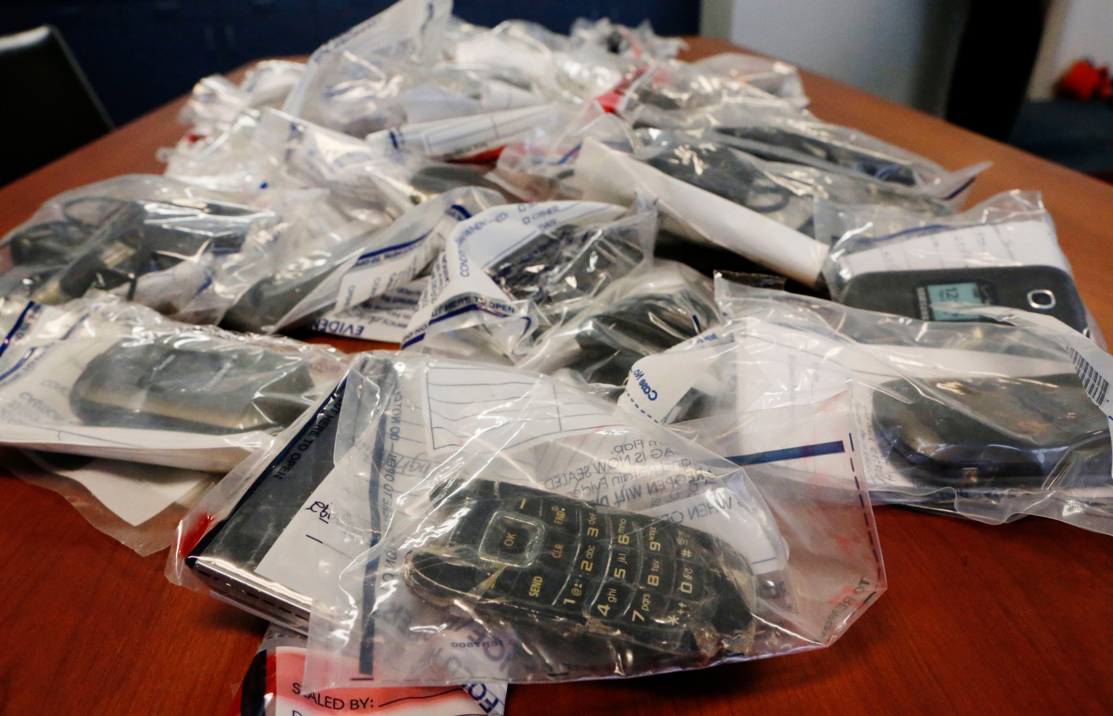 Confiscated cell phones were on display at a 2015 press conference. Federal authorities had obtained indictments that allege two groups of inmates used cell phones inside state prisons to run a drug ring across the metro area and perpetrate fraud schemes against individuals outside the prison walls. BOB ANDRES / BANDRES@AJC.COM