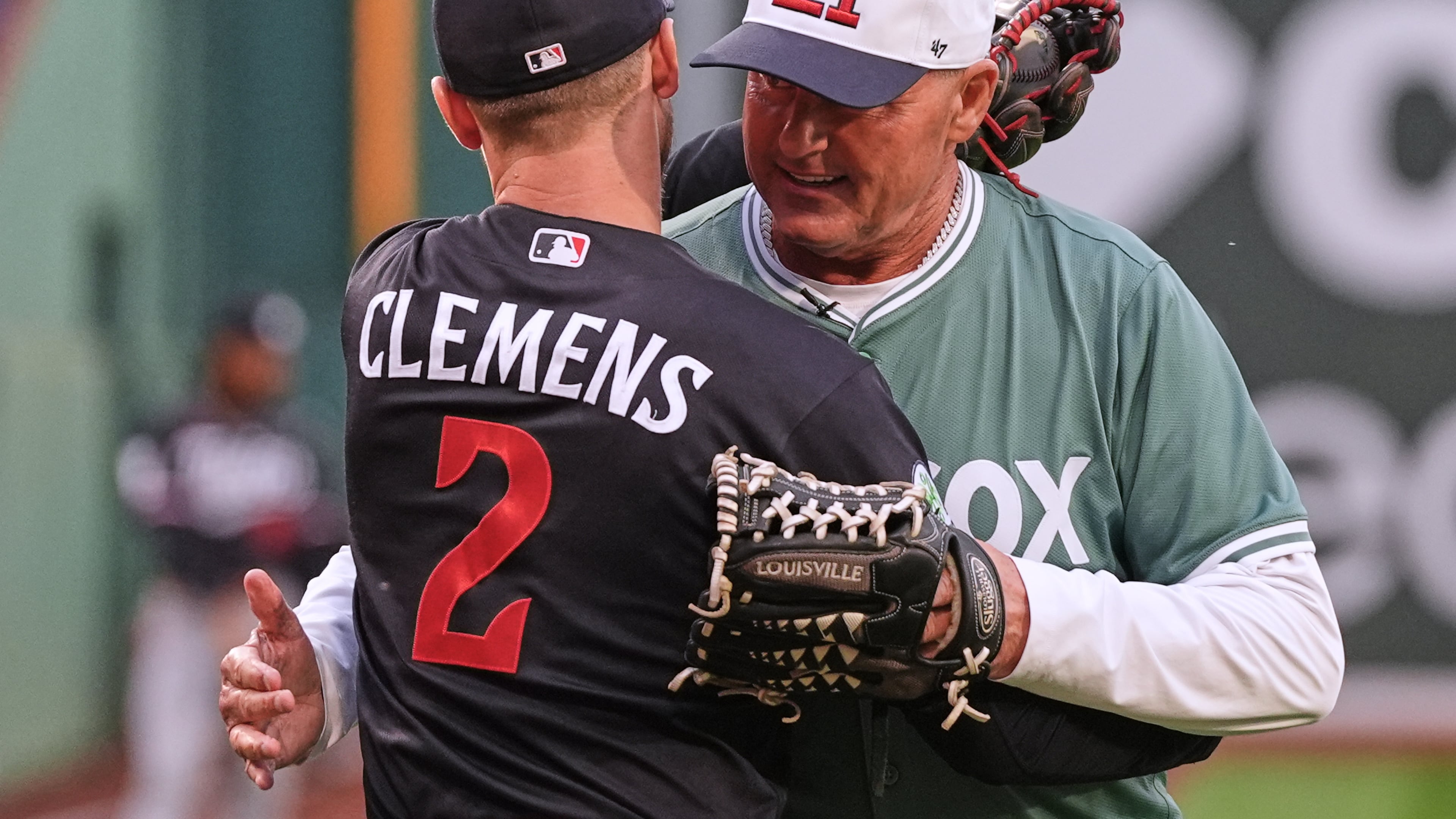 Former Boston Red Sox pitcher Roger Clemens, right, embraces his son, left, Minnesota Twins' Kody Clemens (2), after throwing out a ceremonial first pitch prior to a baseball game between the teams Friday, May 22, 2026, in Boston. (AP Photo/Charles Krupa)
