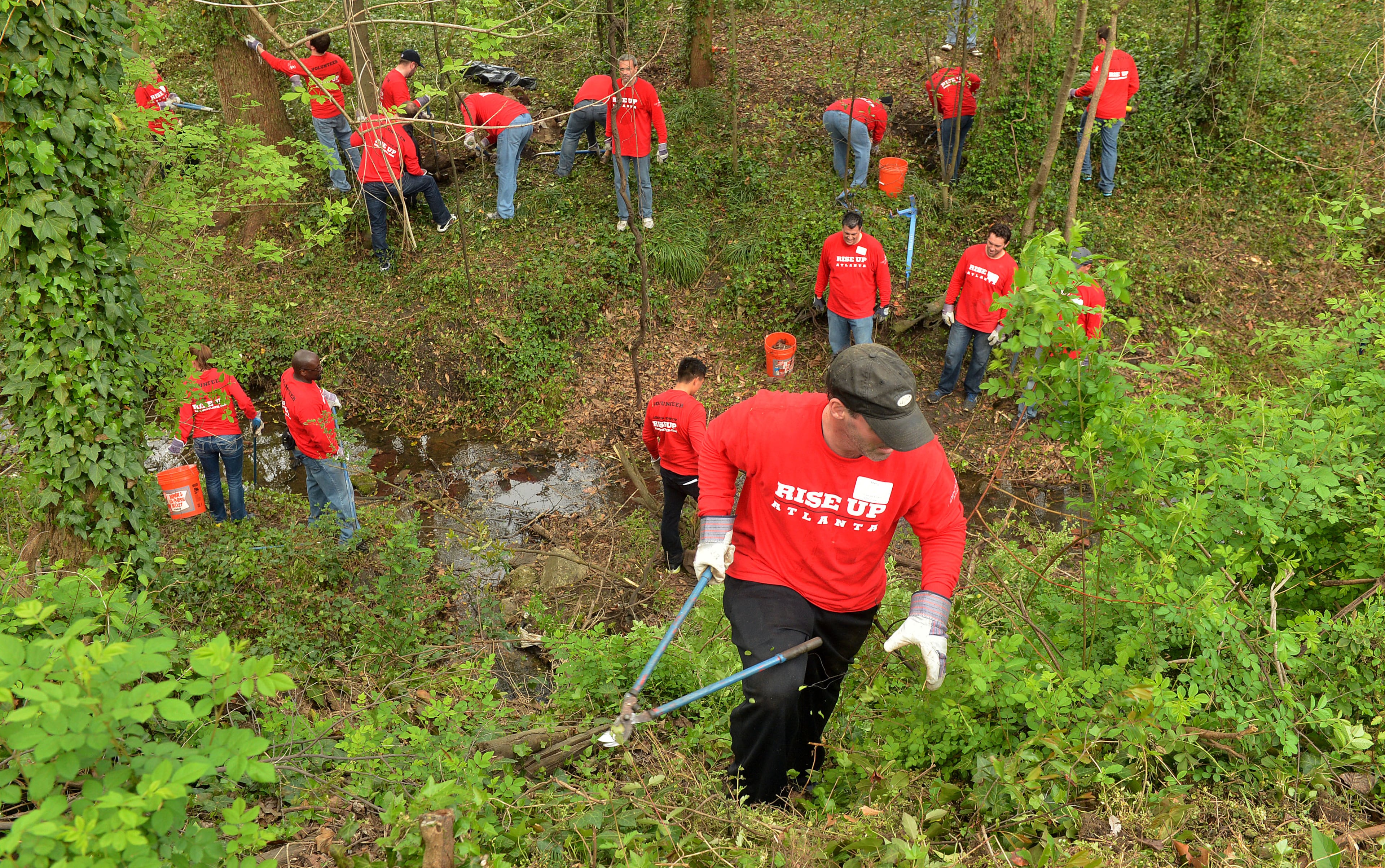 Marty Lauzon uses clippers while clearing a hillside at the site. More than 180 associates of the Blank Family of Businesses laid the groundwork for the first park for current residents of the English Avenue community of Atlanta Friday, April 4, 2014. During its Sixth Annual All-Associates Day, volunteers from all of the businesses, including Arthur Blank, Mike Smith, Thomas Dimitroff and Rich McKay grabbed rakes, shovels, paint brushes and weed trimmers to start to build Lindsay Street Park in the English Avenue neighborhood. In addition, other Blank associates added an artistic element to the park utilizing an abandoned house on the site, painting and transforming it into a temporary art installation with the help of Dashboard Co-op. The English Avenue area currently does not have a park of its own, and this addition will provide important greenspace and recreational opportunities to improve the health and quality of life of its residents.