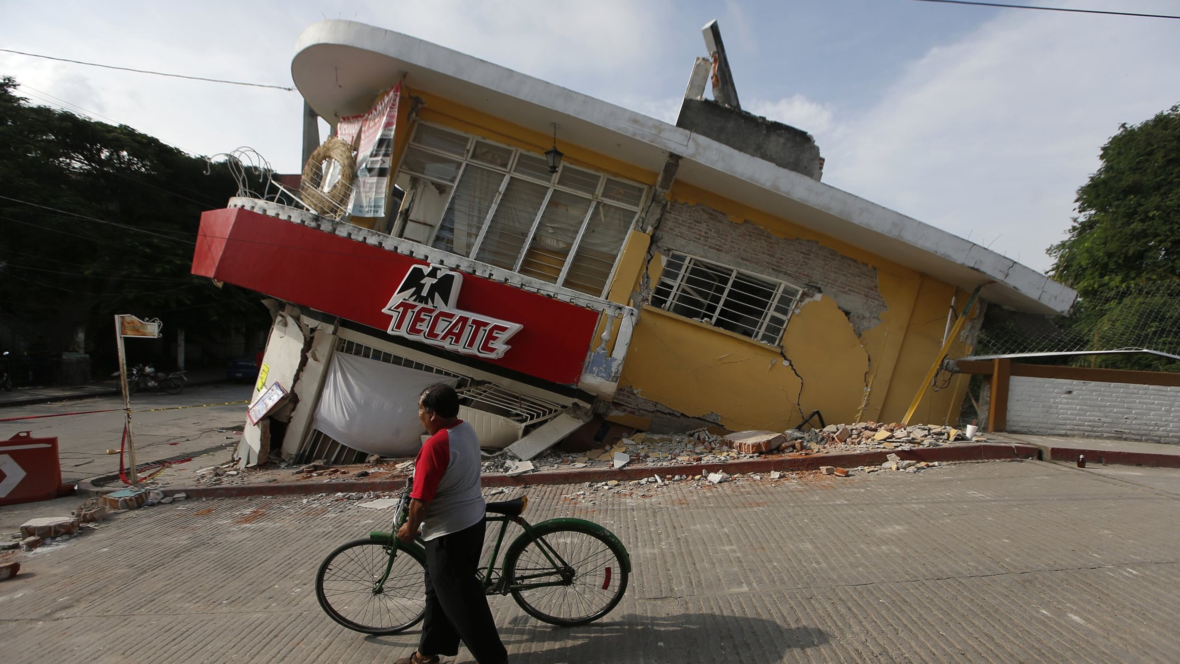 A man walks his bike past a building felled by a 7.1 earthquake, in Jojutla, Morelos state, Mexico, Wednesday, Sept. 20, 2017. Police, firefighters and ordinary Mexicans are digging frantically through the rubble of collapsed schools, homes and apartment buildings, looking for survivors of Mexico’s deadliest earthquake in decades as the number of confirmed fatalities climbs. (AP Photo/Eduardo Verdugo)