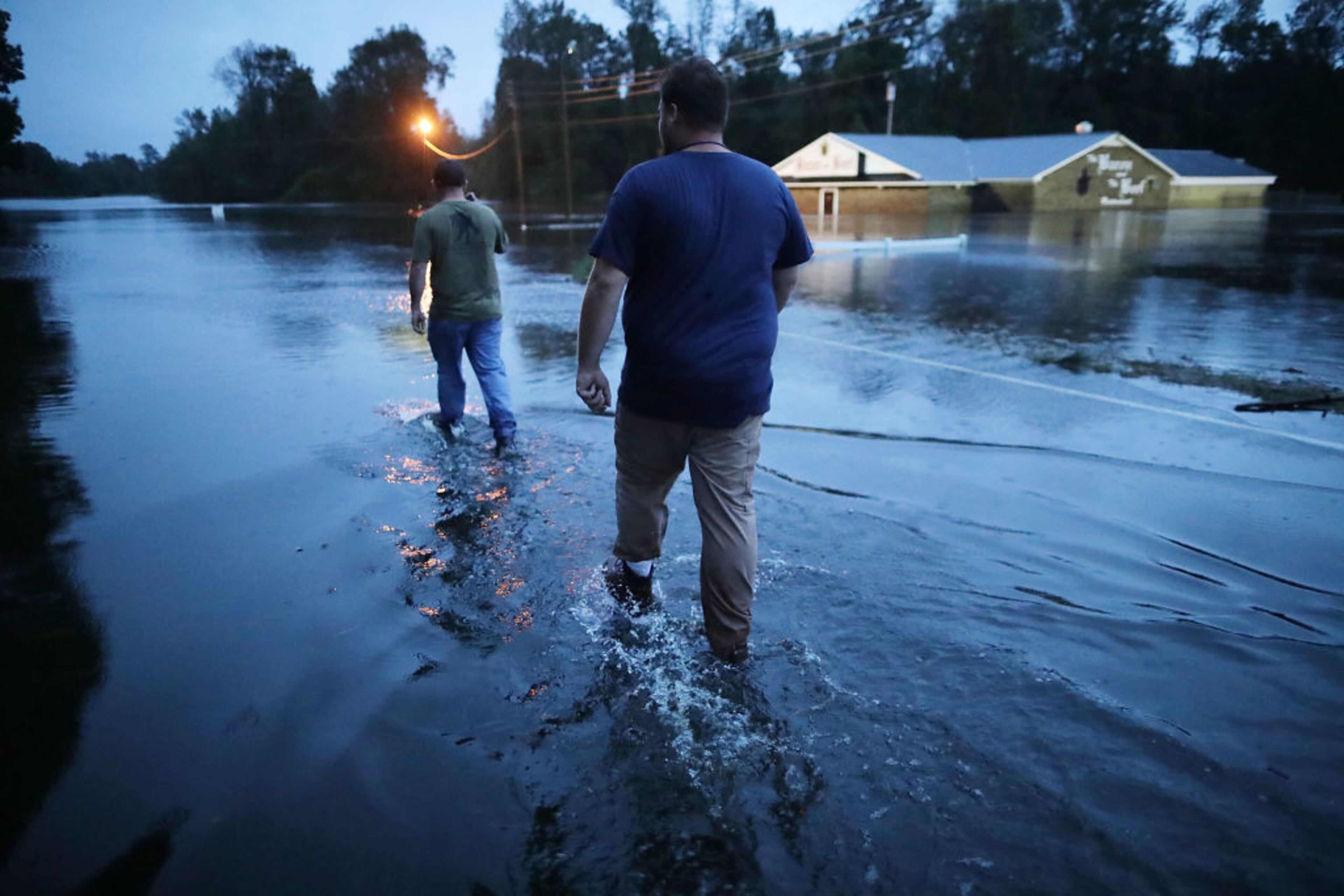 KINSTON, NC - SEPTEMBER 15: Rescue volunteers wade in water while looking for a way around Highway 70 where the Neuse River had flooded the road September 15, 2018 in Kinston, North Carolina. Hurricane Florence made landfall in North Carolina as a Category 1 storm Friday and at least 12 deaths have been attributed to the storm, which continues to produce heavy rain and strong winds extending out nearly 200 miles. (Photo by Chip Somodevilla/Getty Images)