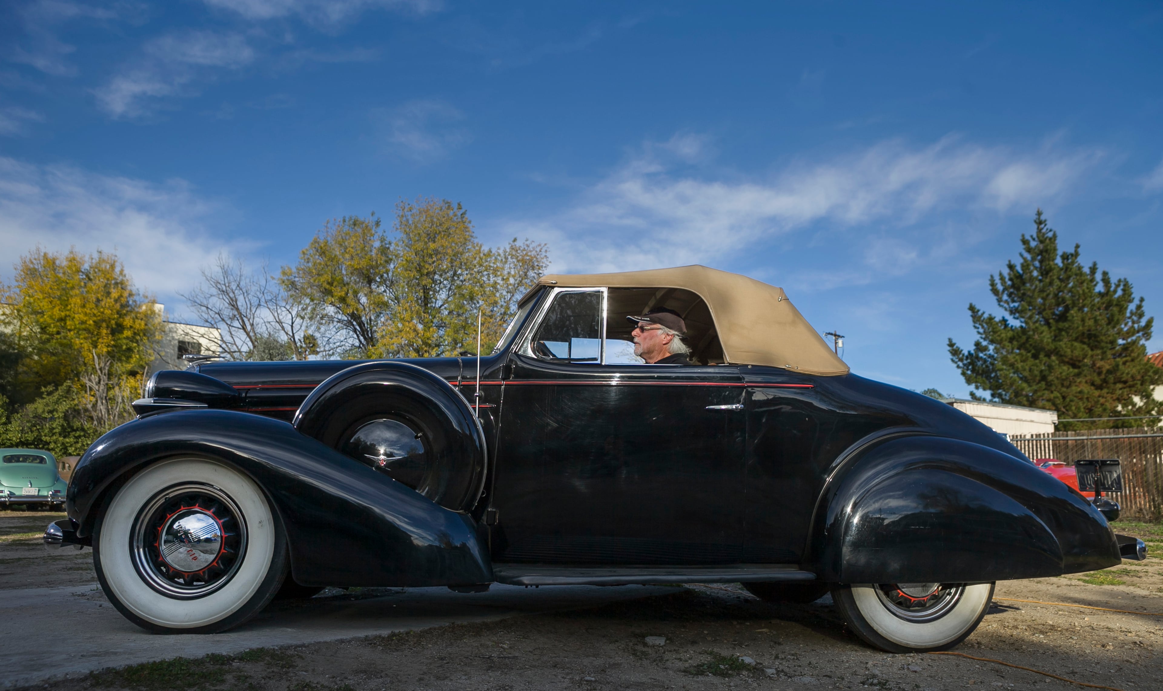 In this photo taken Monday, Jan. 7, 2013, car collector, Garvin Kotzin, 63, who owns several cars featured in the "Gangster Squad" film, poses with his 1936 Oldsmobile convertible in Los Angeles.