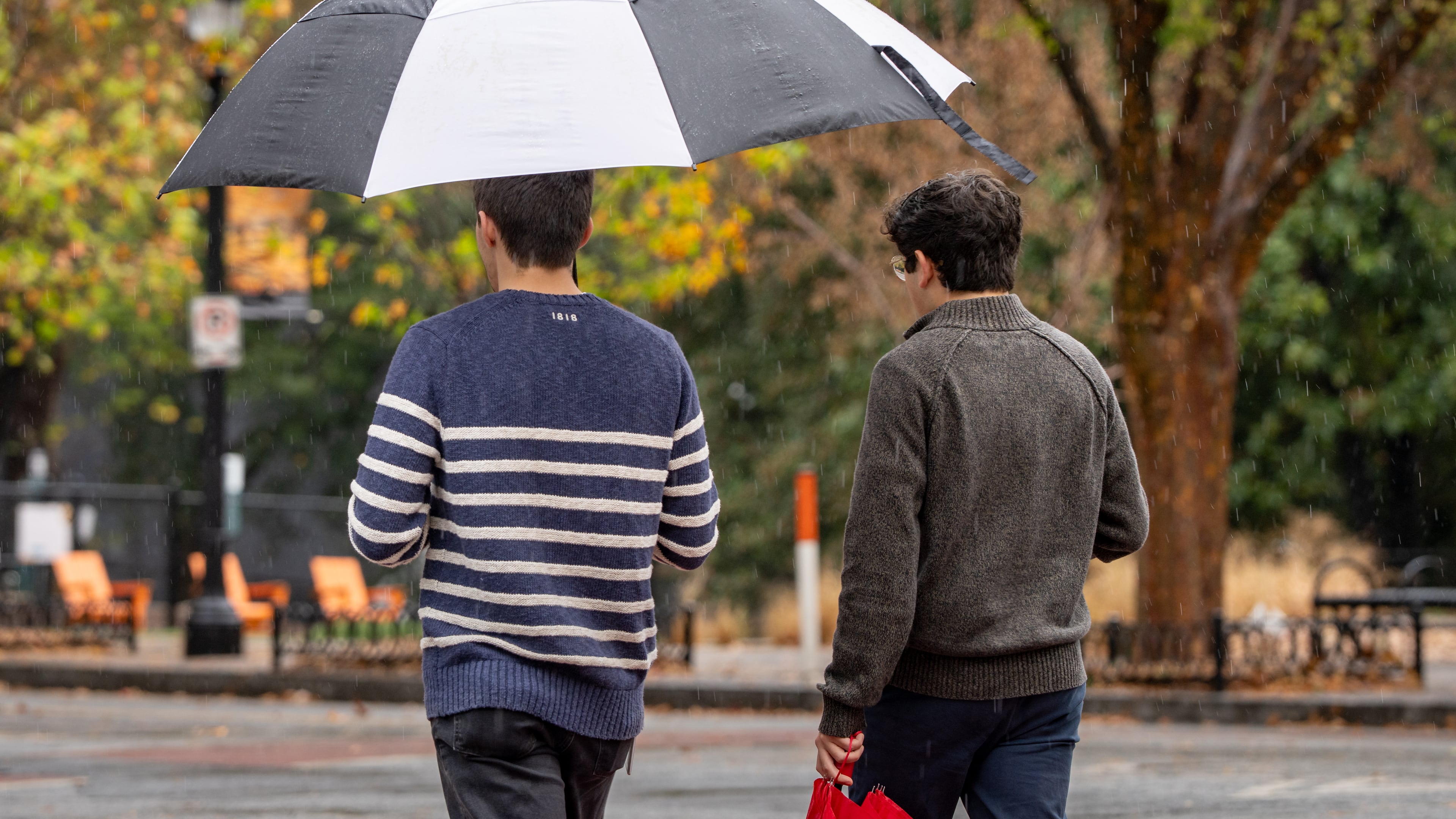 Two men walk across 10th street in the rain. Tuesday, November 25, 2025. (Ben Hendren for the AJC)