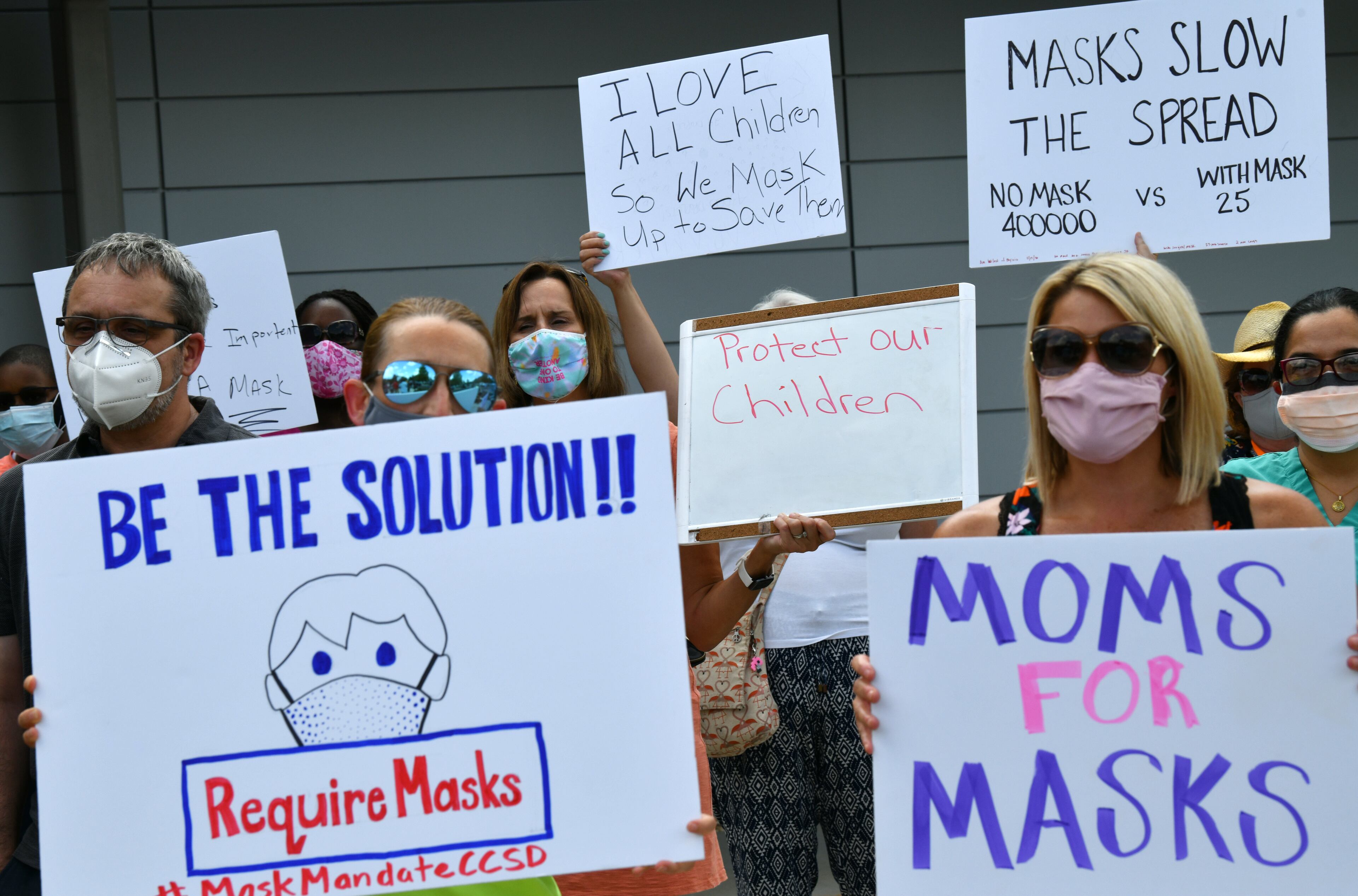 Parents hold a rally to encourage the Cobb County School District to require masks for students and staff at the parking lot of the district's headquarters on Aug. 2, 2021. (Hyosub Shin / Hyosub.Shin@ajc.com)