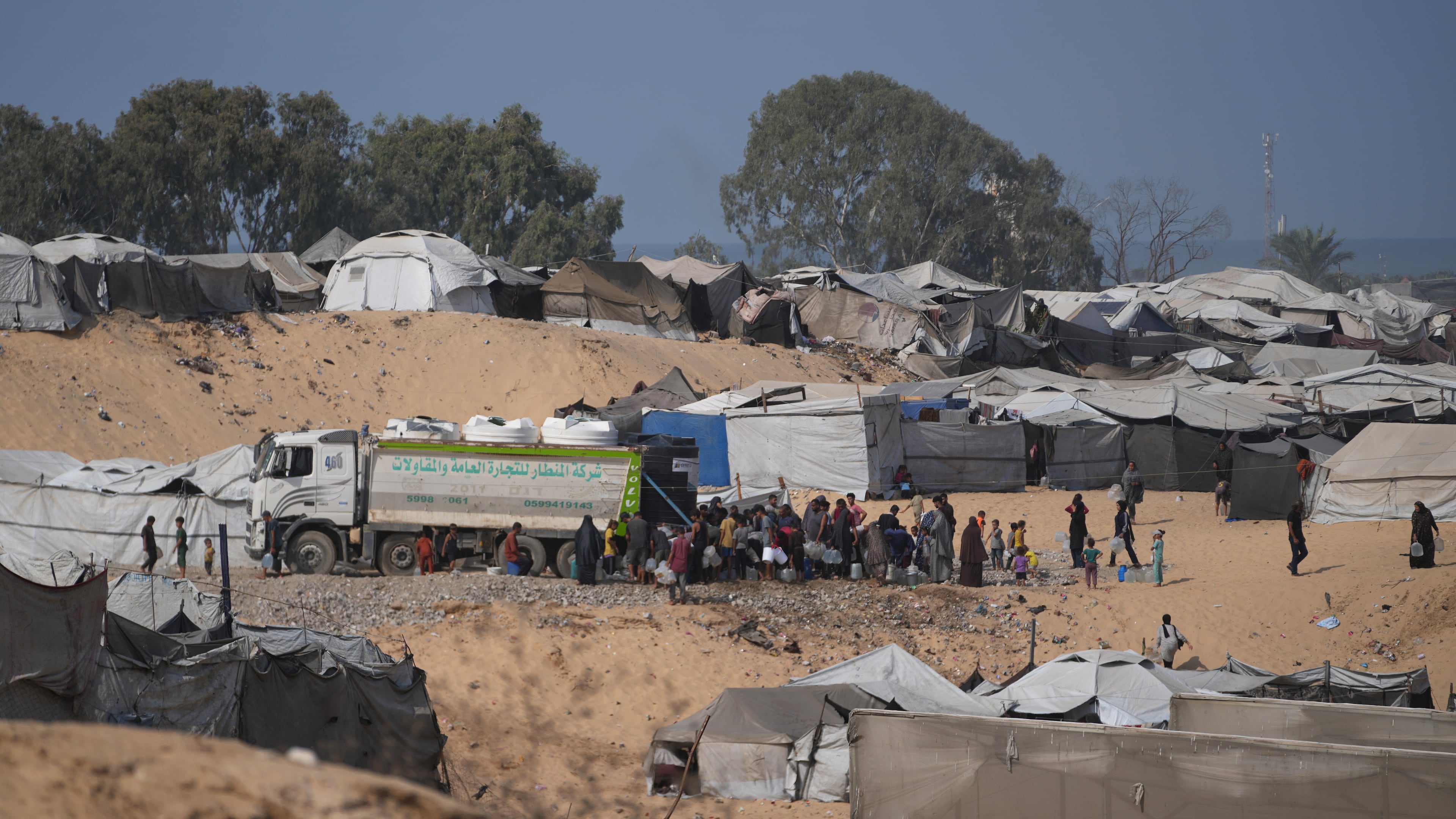 Displaced Palestinians gather to fill containers with fresh water from a supplier in Deir al-Balah, central Gaza Strip, Saturday, Oct. 10, 2026. (AP Photo/Abdel Kareem Hana)