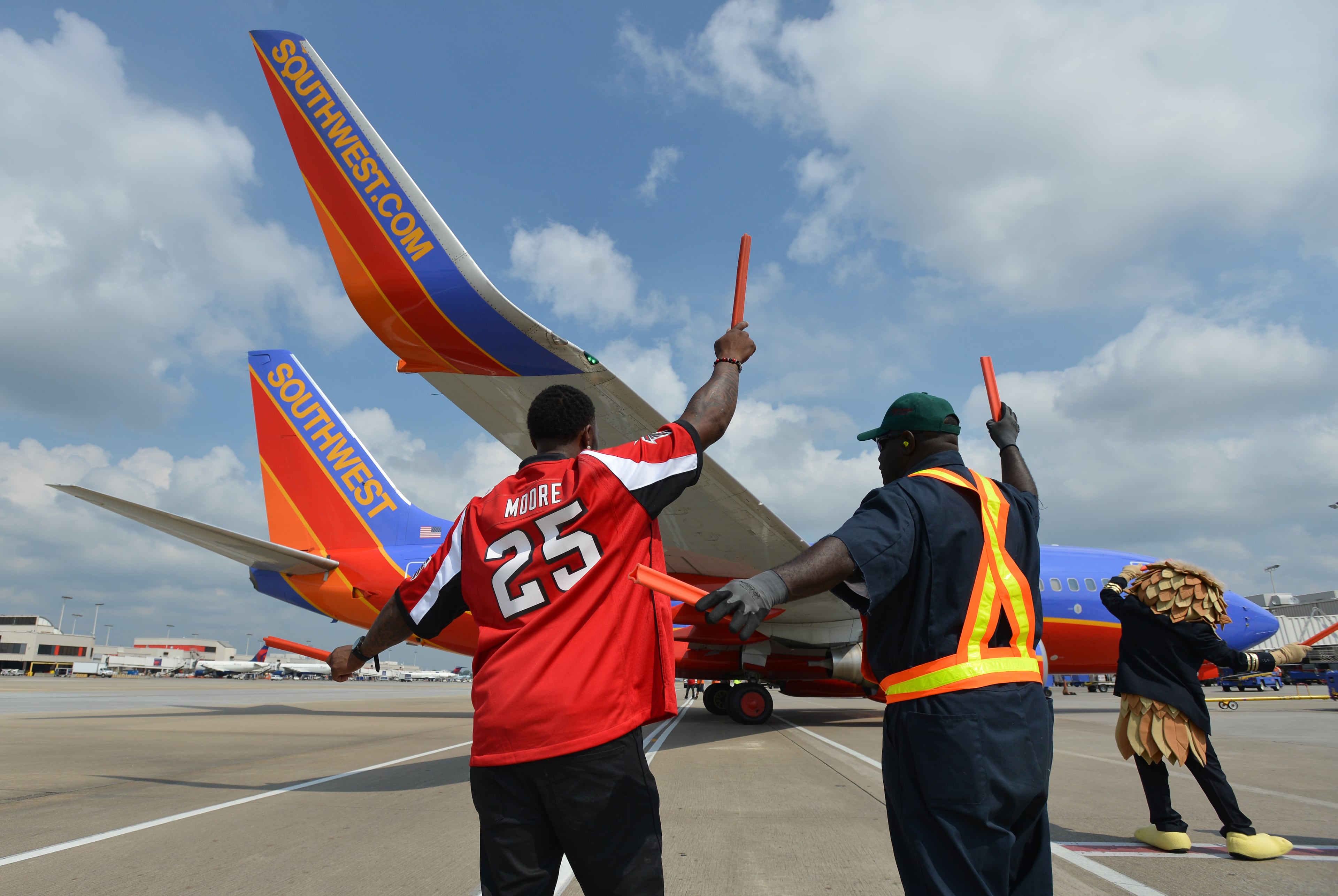 Atlanta Falcons receiver Harry Douglas helps ramp agent Milton Smith direct a Southwest Airlines 737 away from the terminal. Five members of the Atlanta Falcons visited Southwest Airlines operations at Hartsfield-Jackson Atlanta International Airport with special guest Jordan Thomas. Thomas, 14, was diagnosed with cancer in 2012. As part of the Make-A-Wish Foundation, Thomas had the opportunity to hang out with members of the Falcons as they visited the Southwest ticket counter terminal, announced a flight departure and helped direct a plane away from the terminal. BRANT SANDERLIN /BSANDERLIN@AJC.COM