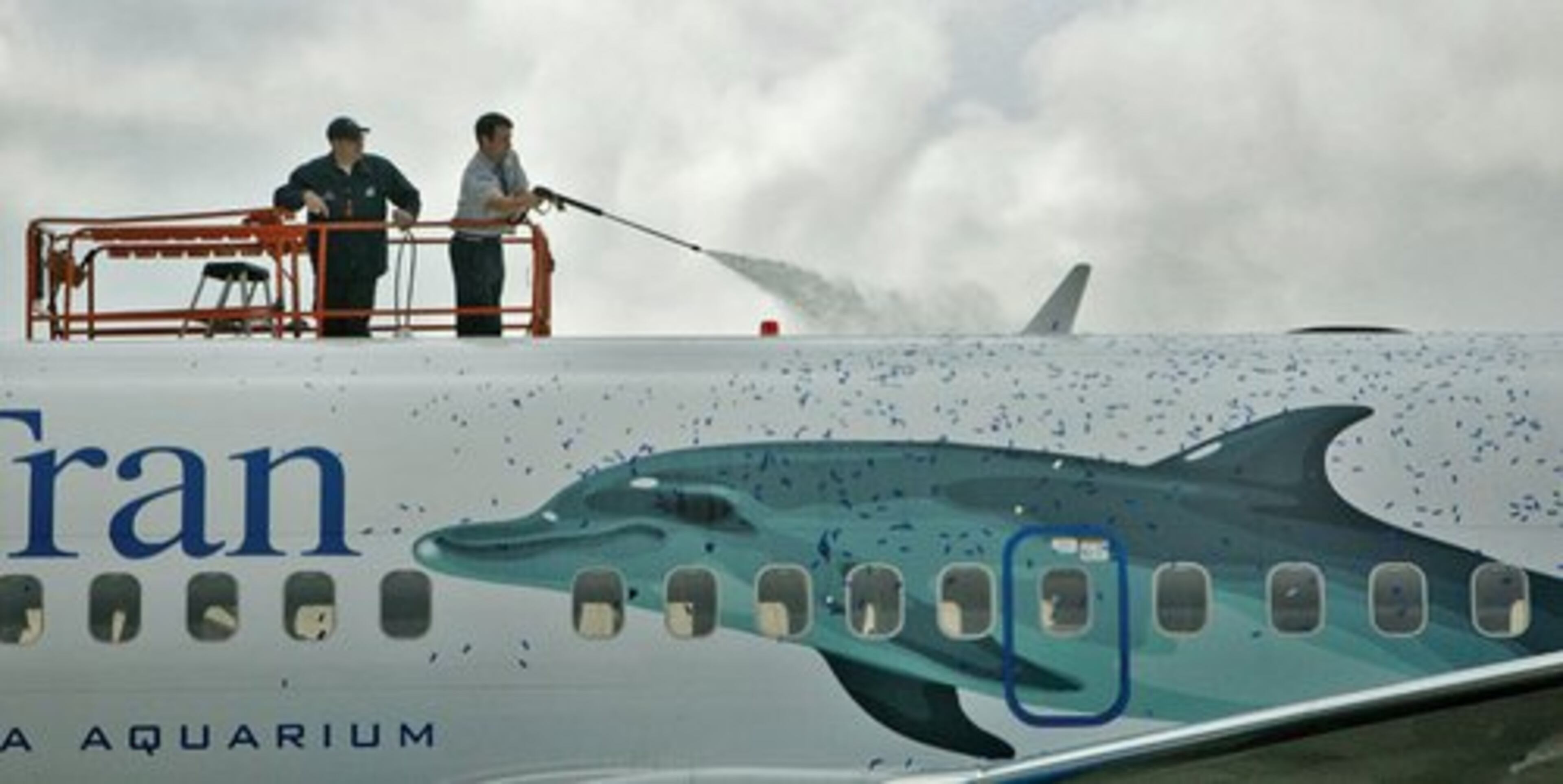 After the ceremony unveiling Dolphin 1, workers used blowers and pressure washers to remove confetti that was stuck to the aircraft after it was dropped from the ceiling of the hanger.