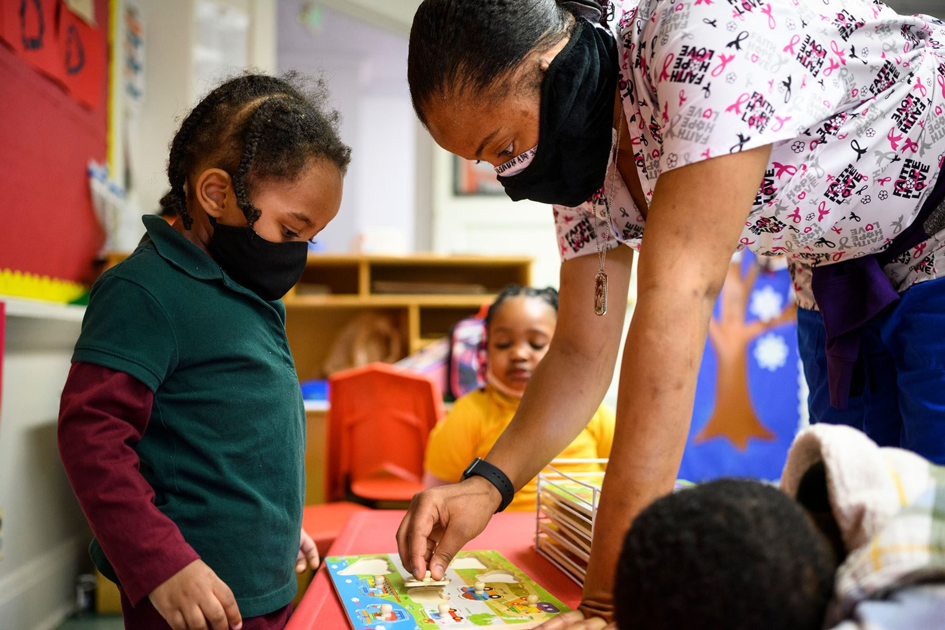 A teacher helps a child solve a puzzle at a Baltimore daycare in January 2021. (MATT ROTH/THE WASHINGTON POST/GETTY IMAGES)