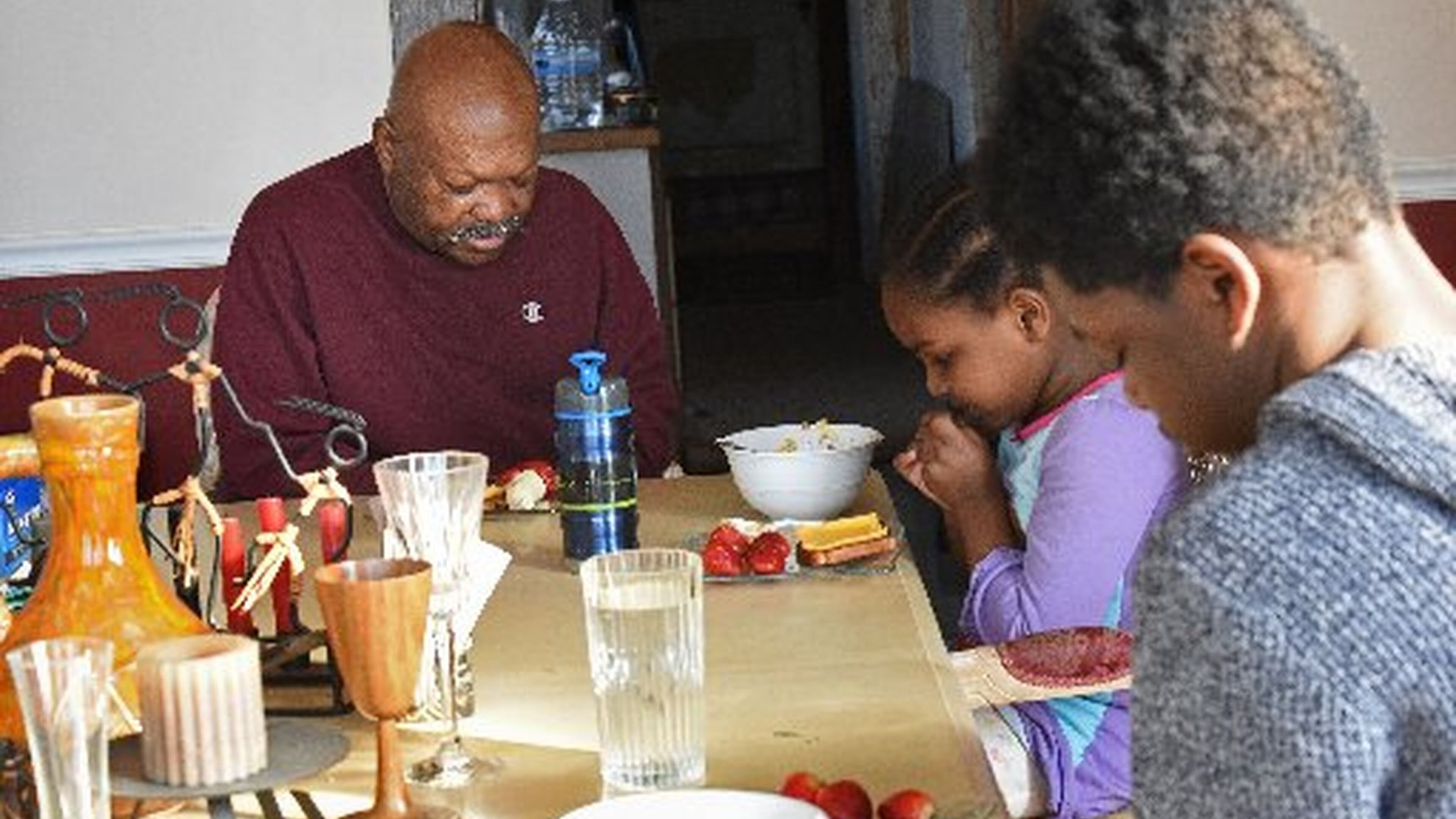 Eugene Vickerson and his grandchildren Jakari and Amore, shown in a 2016 file photo, pray together before eating breakfast. Georgia has increased its efforts to place children with grandparents or other relatives. HYOSUB SHIN / HSHIN@AJC.COM