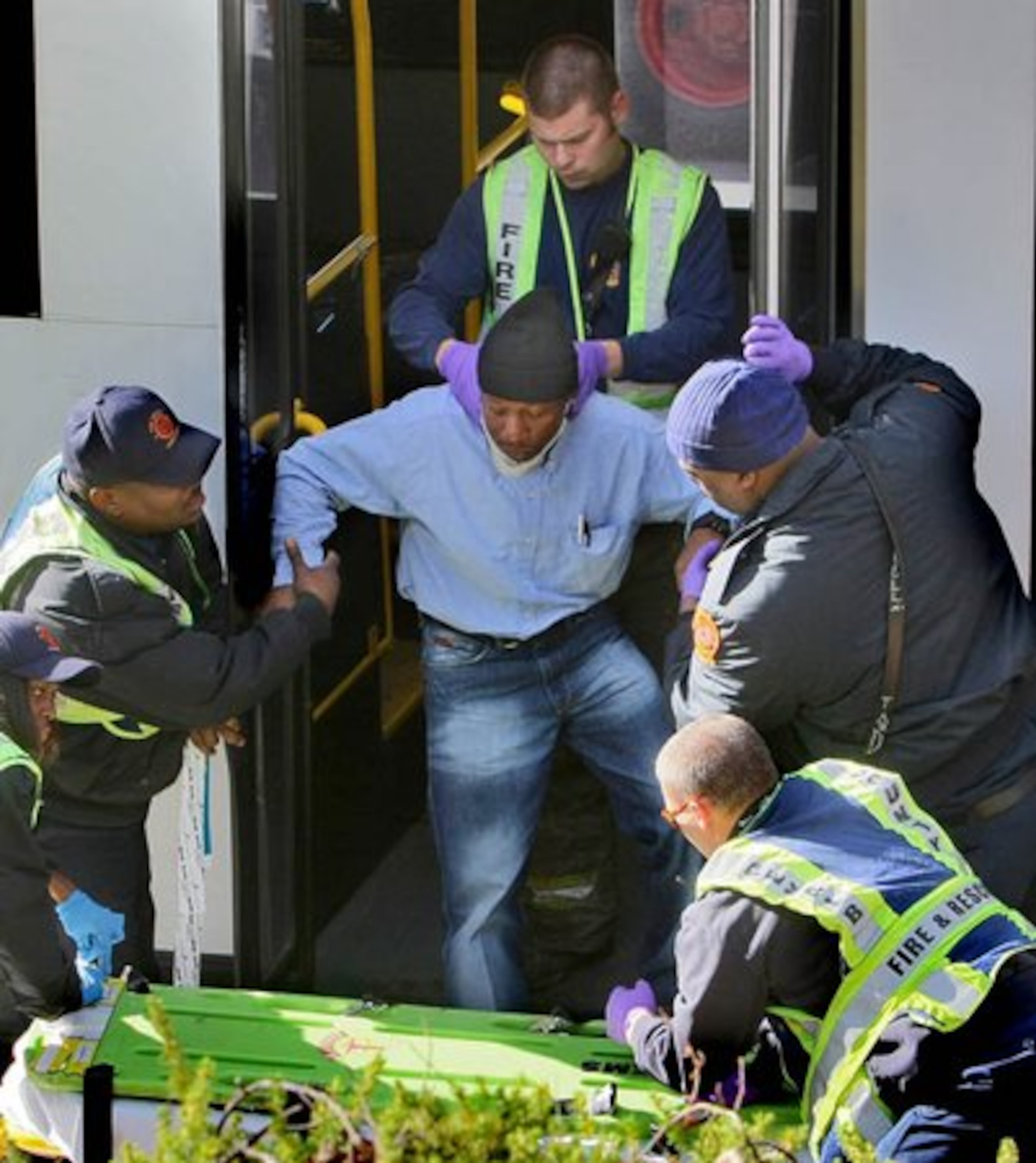Emergency workers help a passenger off the bus.