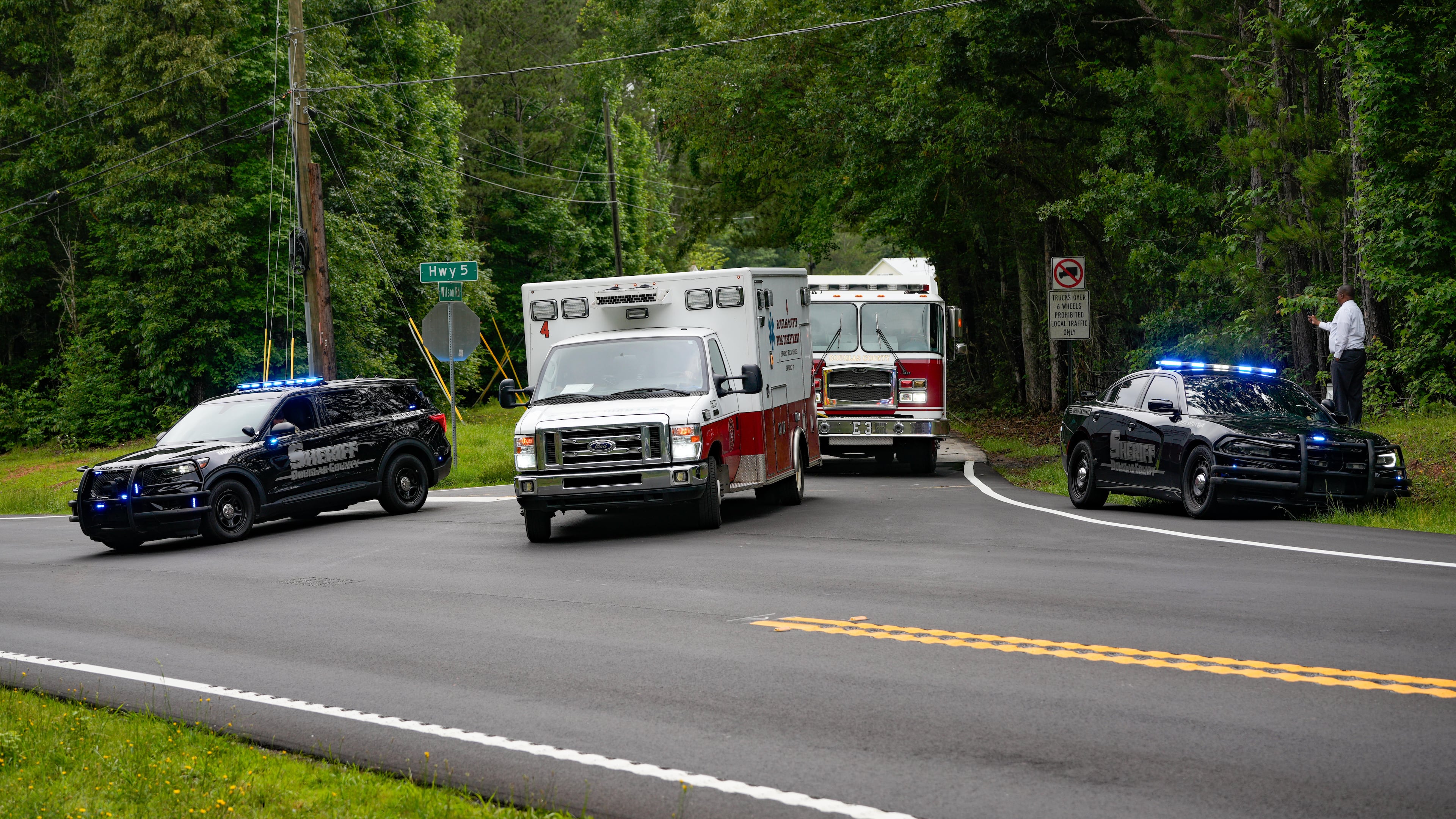 Law enforcement vehicles block Wilson Road in Douglas County after a big rig overturned. The truck was carrying hazardous materials, and officials asked nearby residents to evacuate Friday. (Ben Hendren for The AJC)