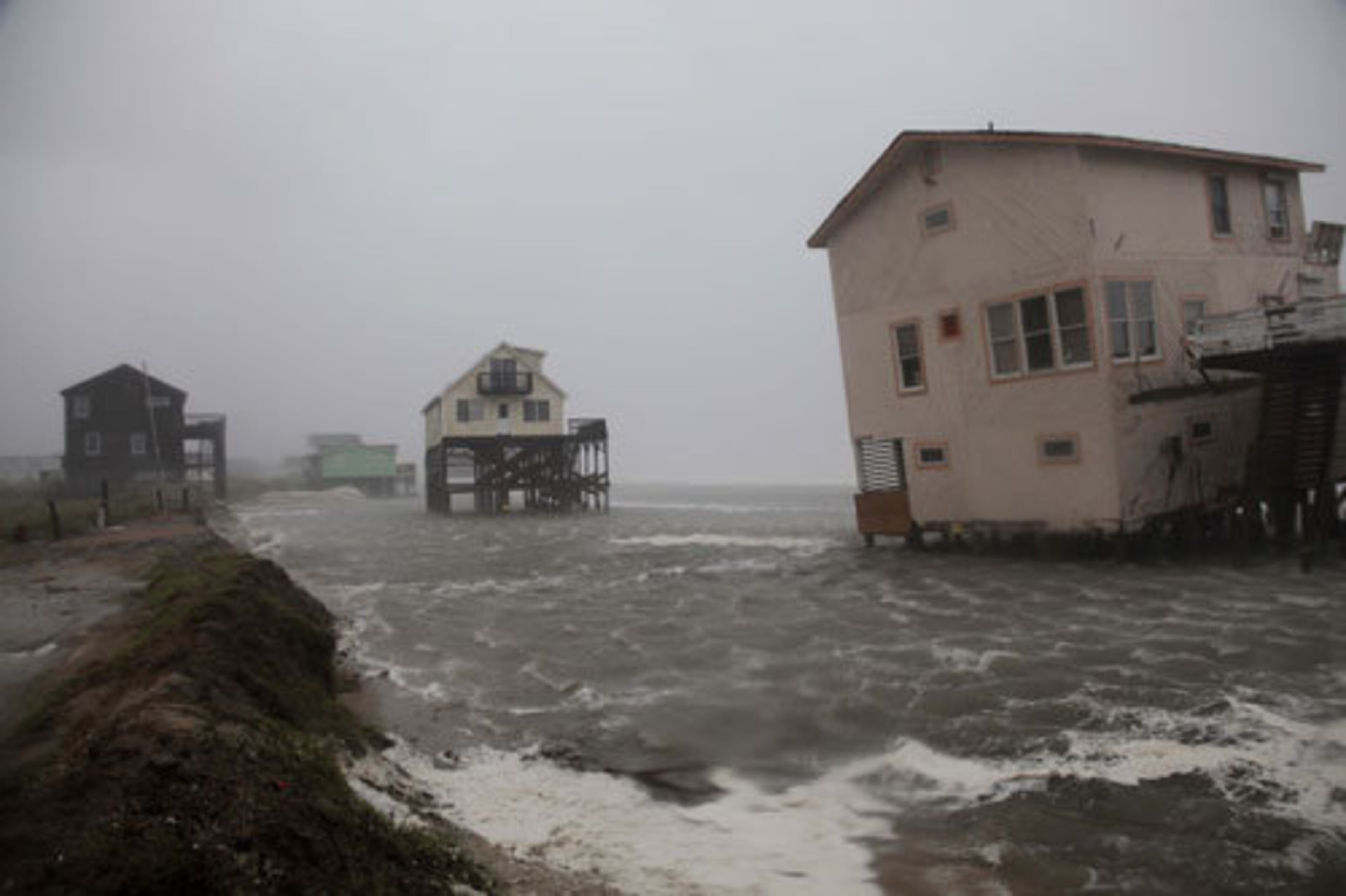 Abandoned beach front houses are surrounded by rising water as the effects of Hurricane Irene are felt in Nags Head, N.C., Saturday, Aug. 27, 2011. Irene slammed into North Carolina's coast around dawn Saturday with howling winds and drenching rains amid reports of flooding and tens of thousands of people without power.