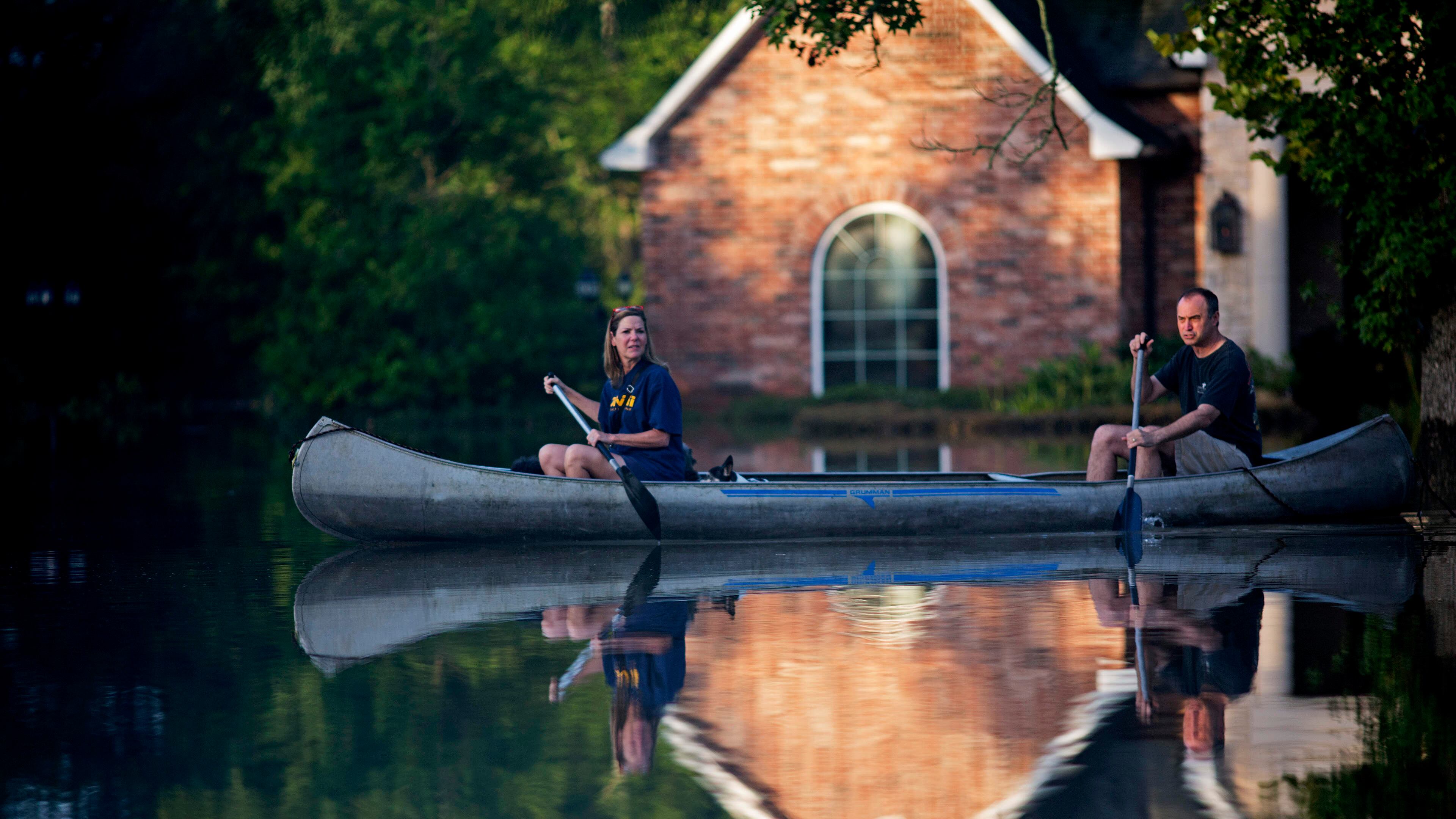 Danny and Alys Messenger canoe away from their flooded home after reviewing the damage in Prairieville, La., Tuesday, Aug. 16, 2016. As waters begin to recede in parts of Louisiana, some residents struggled to return to flood-damaged homes on foot, in cars and by boat. (AP Photo/Max Becherer)