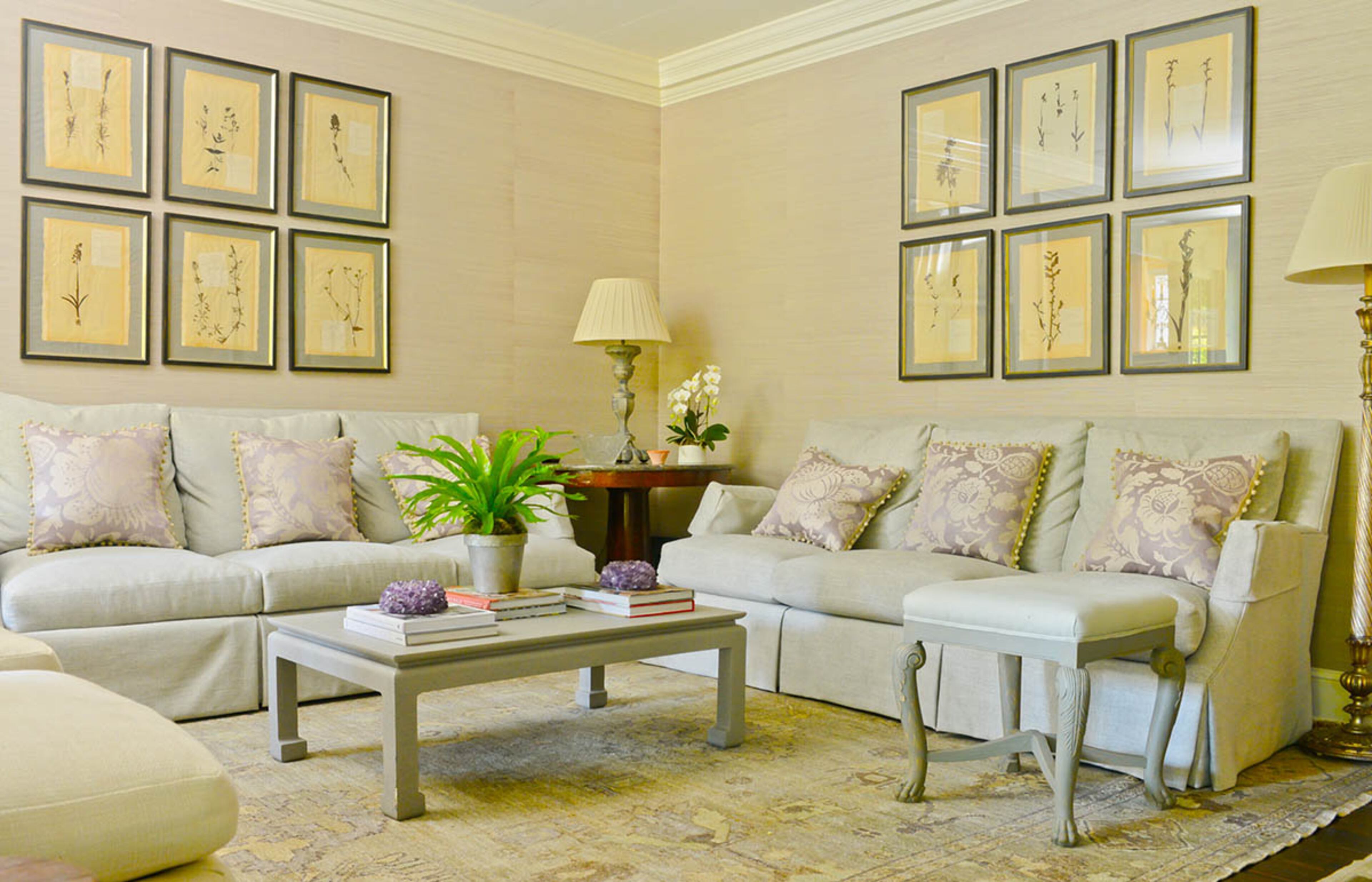 A rug from Keivan Woven Arts covers the dark wood floors in the living room. The light rug and neutral furniture form a backdrop for calm accents of lavender, including botanical prints on the walls, throughout the room.