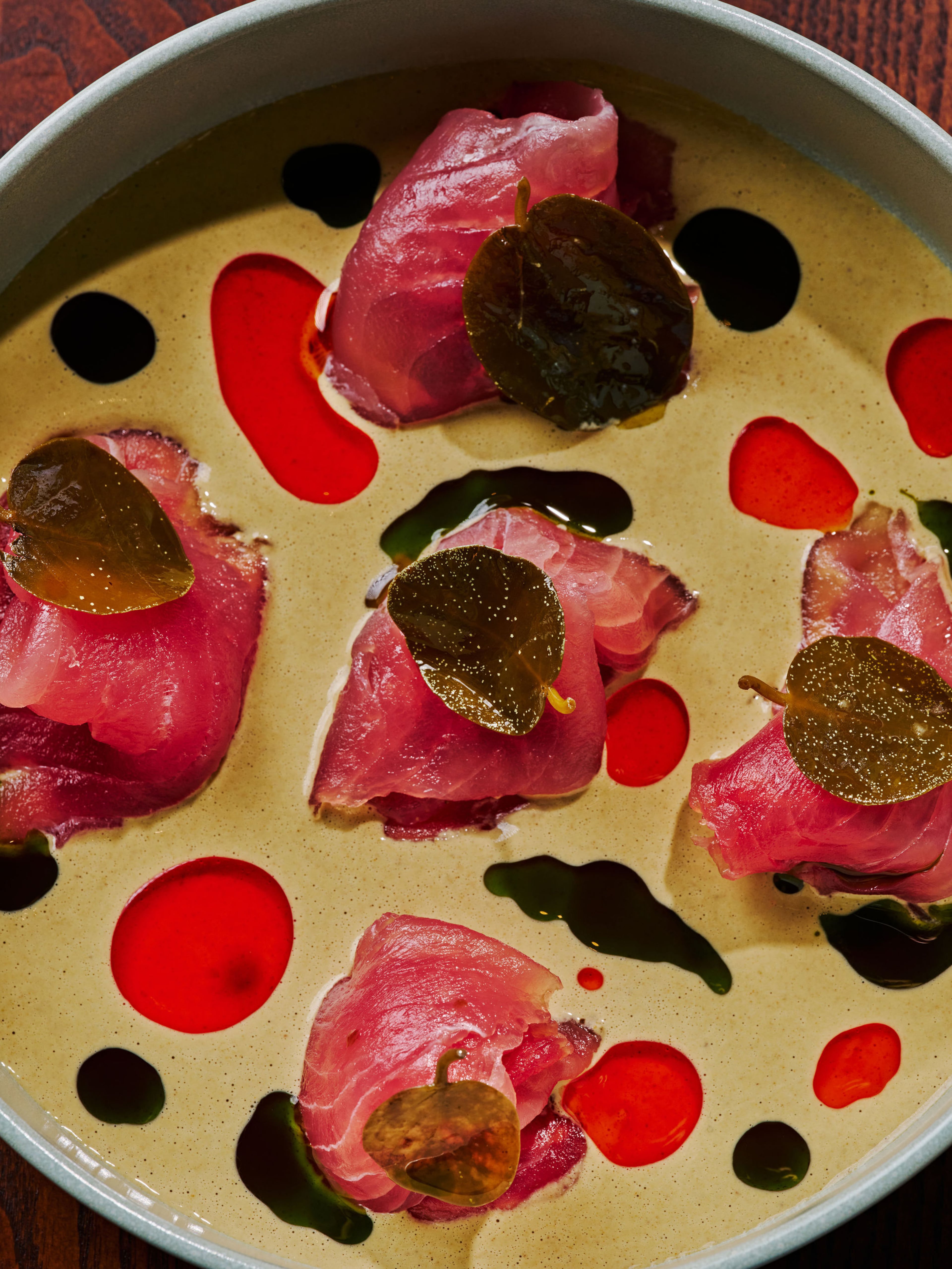 Füm’s artistic tuna carpaccio is plated with little piles of thinly sliced tuna topped with nasturtium leaves and surrounded by swirls of colorful sauce. (Courtesy of Füm)