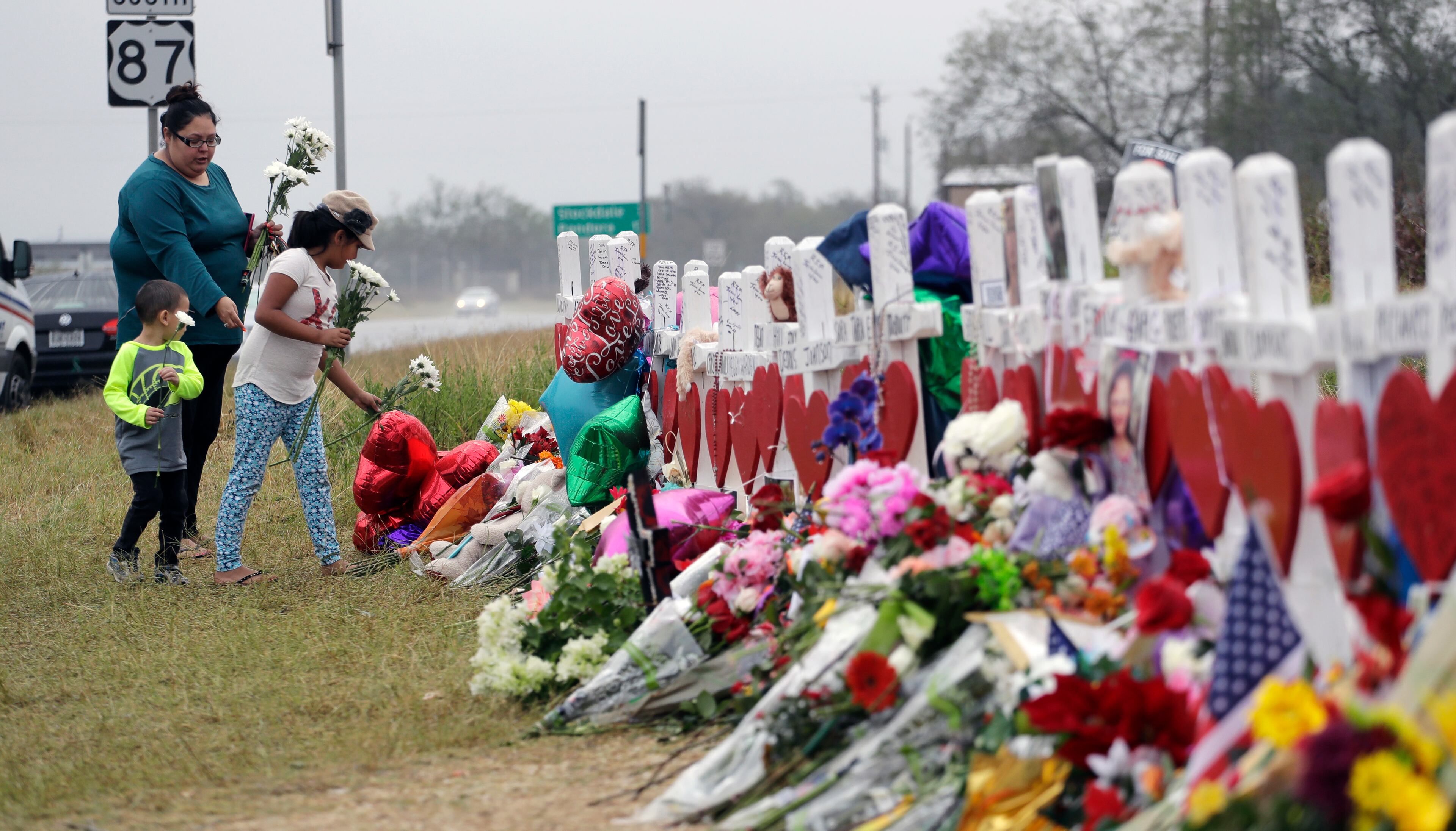 Christina Osborn and her children Alexander Osborn and Bella Araiza visit a makeshift memorial for the victims of the shooting at Sutherland Springs Baptist Church, Sunday, Nov. 12, 2017, in Sutherland Springs, Texas. A man opened fire inside the church in the small South Texas community a week ago, killing more than two dozen. (AP Photo/Eric Gay)