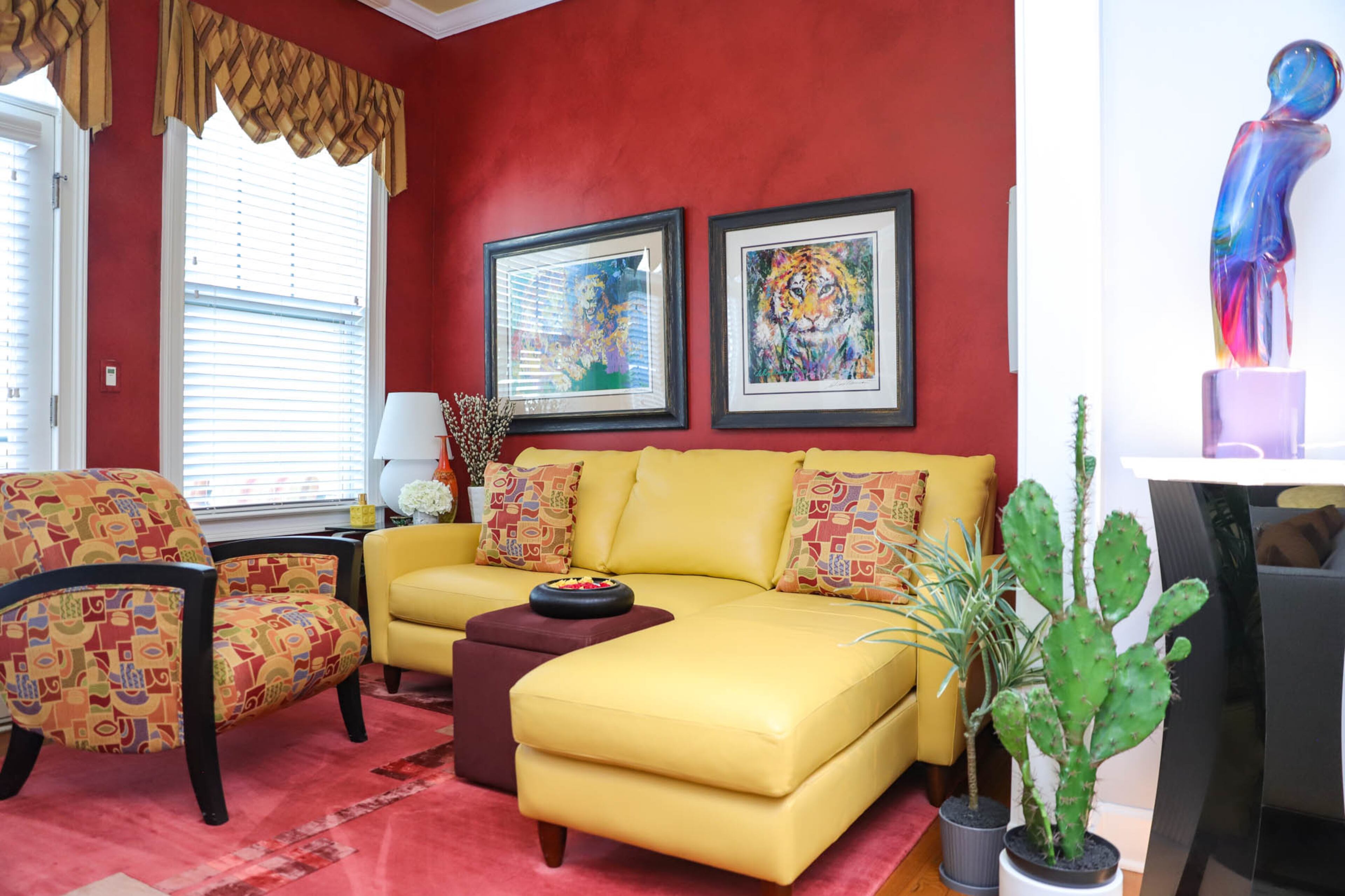 A small red sitting room is tucked off to the side of Stuart and Gwen Witten’s living room, the walls painted with a faux leather finish. A yellow sofa from Cantoni and a custom carpet made in Tibet make the space cozy and bright. The paintings above the sofa are by LeRoy Neiman and the glass sculpture just outside of the red room is by Dino Rosin. Text by Shannon Dominy/Photo by Reynolds Rogers