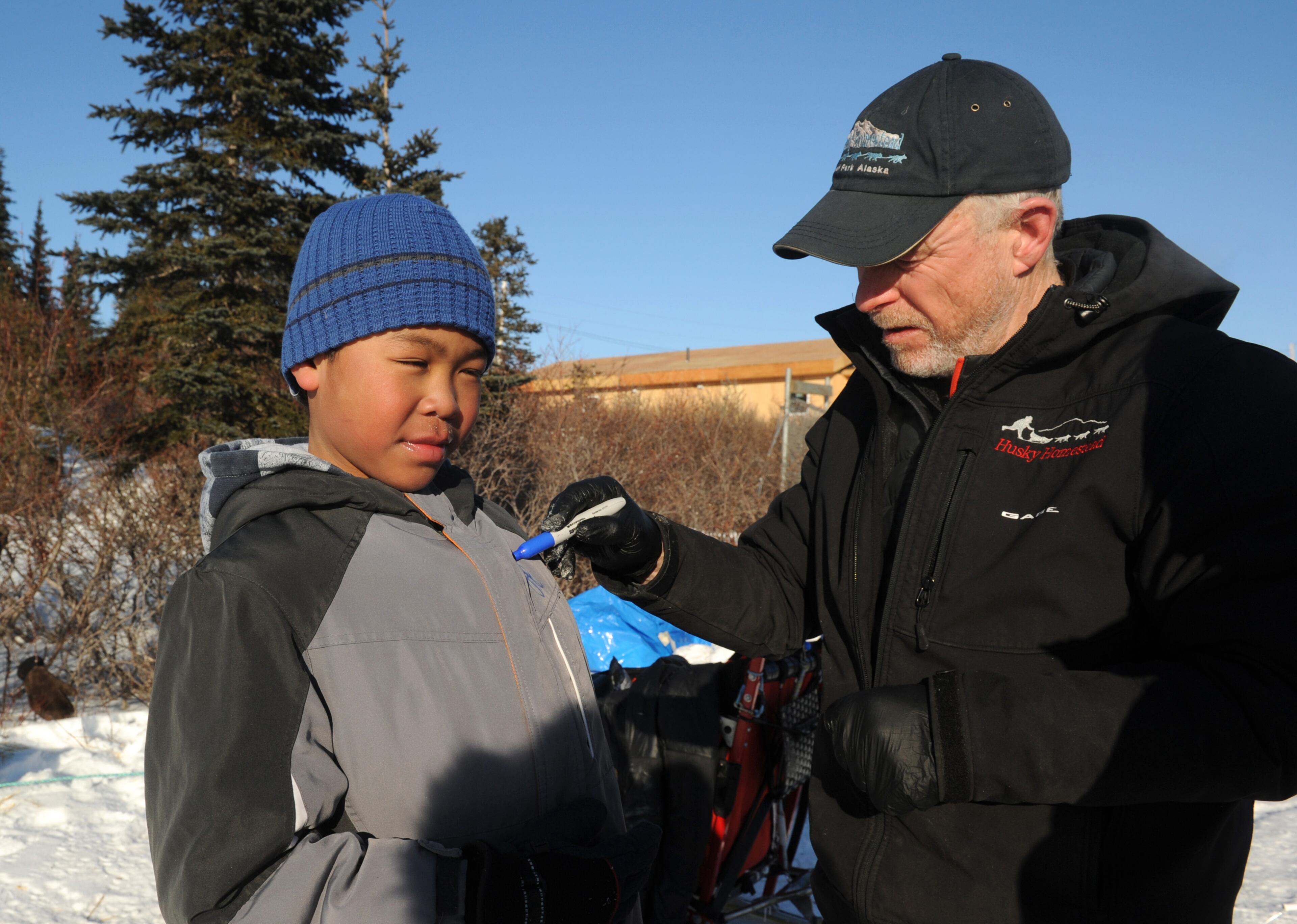 Iditarod musher Jeff King, from Denali, Alaska, signs the jacket of Ben Homekingkeo at the Koyuk checkpoint during the 2014 Iditarod Trail Sled Dog Race on Sunday, March 9, 2014 in Koyuk, Alaska. (AP Photo/The Anchorage Daily News, Bob Hallinen)