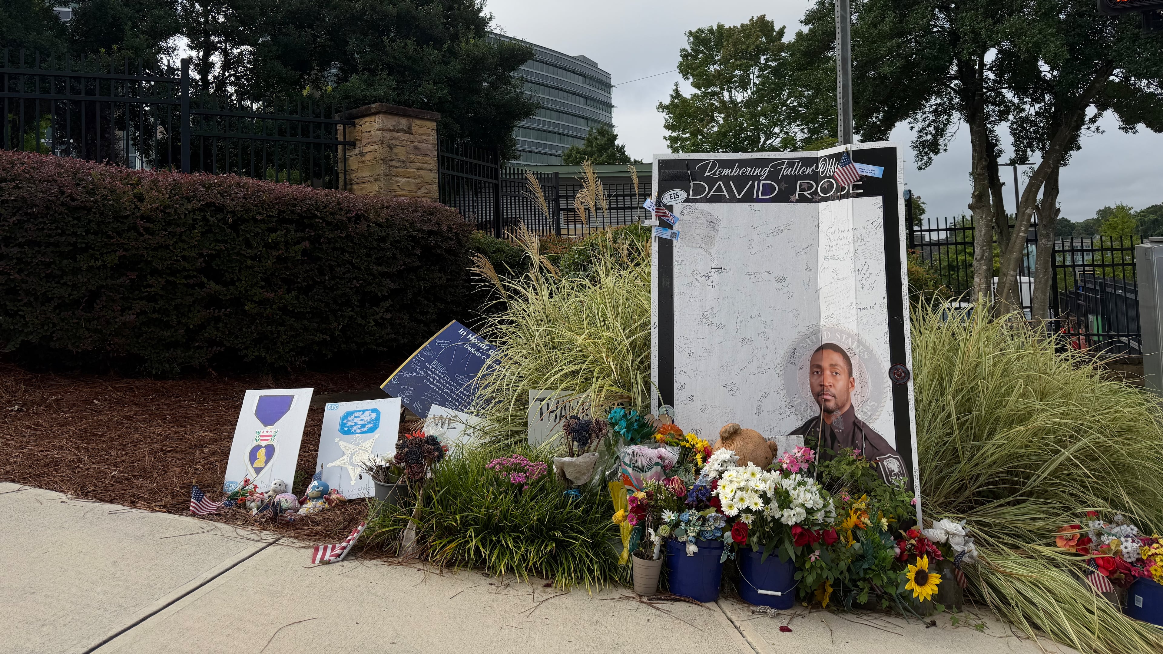 A sign displayed Friday, Aug. 7, 2026, outside the Centers for Disease Control and Prevention in Atlanta commemorates DeKalb County Police Officer David Rose, killed in a shooting a year ago. (Sara Gregory/AJC)
