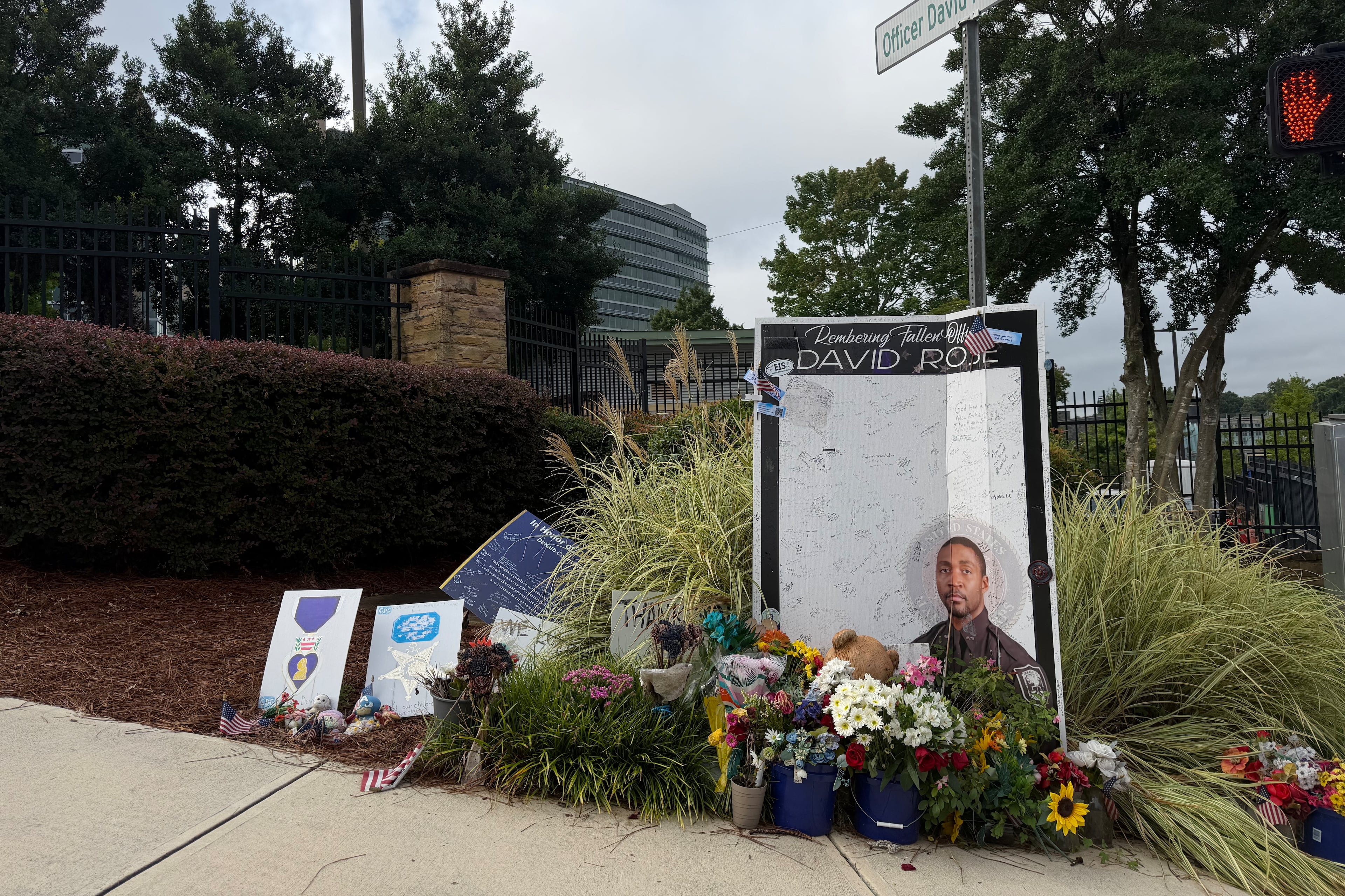 A sign displayed Friday, Aug. 7, 2026, outside the Centers for Disease Control and Prevention in Atlanta commemorates DeKalb County Police Officer David Rose, killed in a shooting a year ago. (Sara Gregory/AJC)