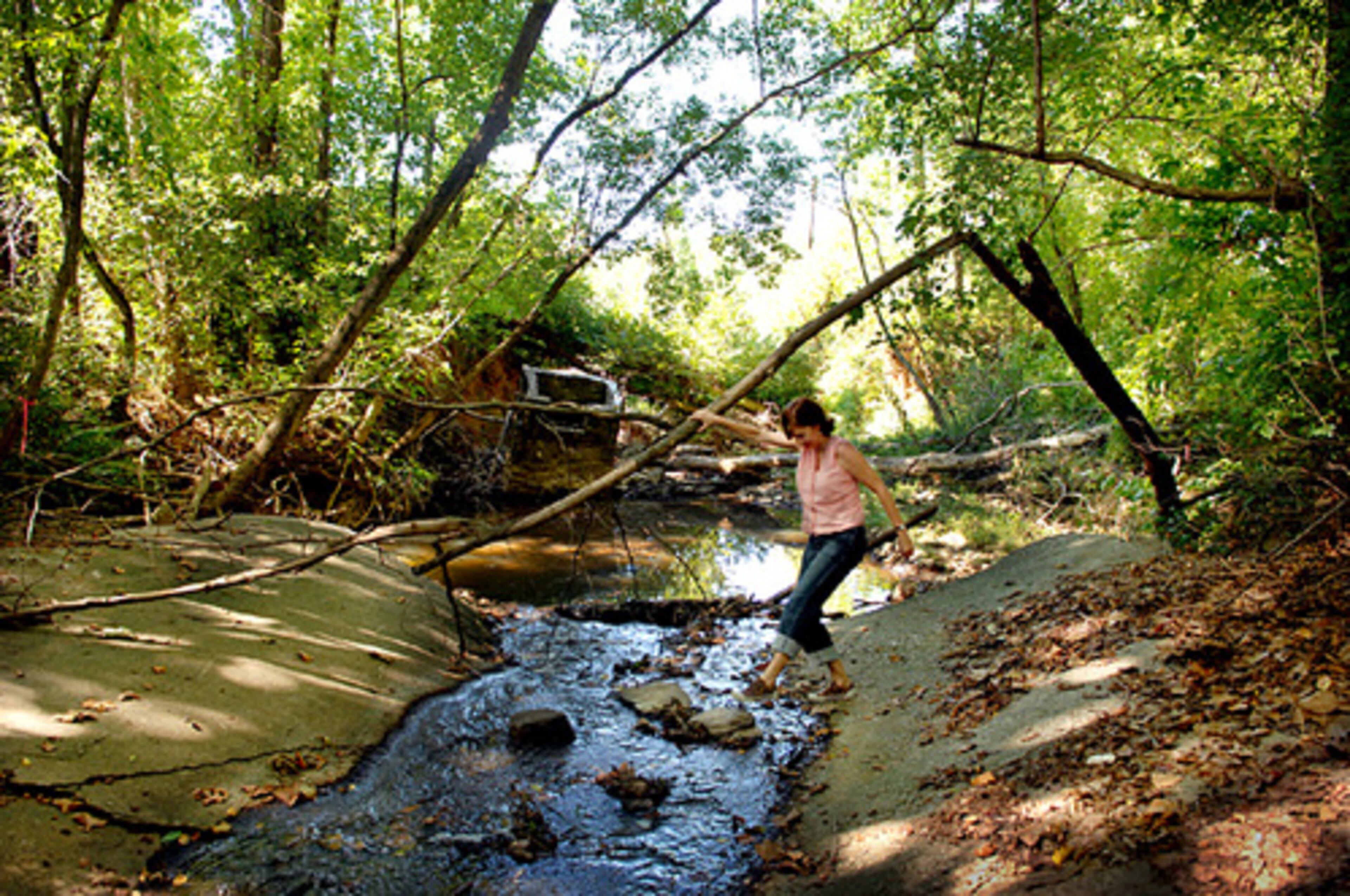 Nancy Moore steps steps over a trickle of water from Lake Moore that flows into Nancy Creek.