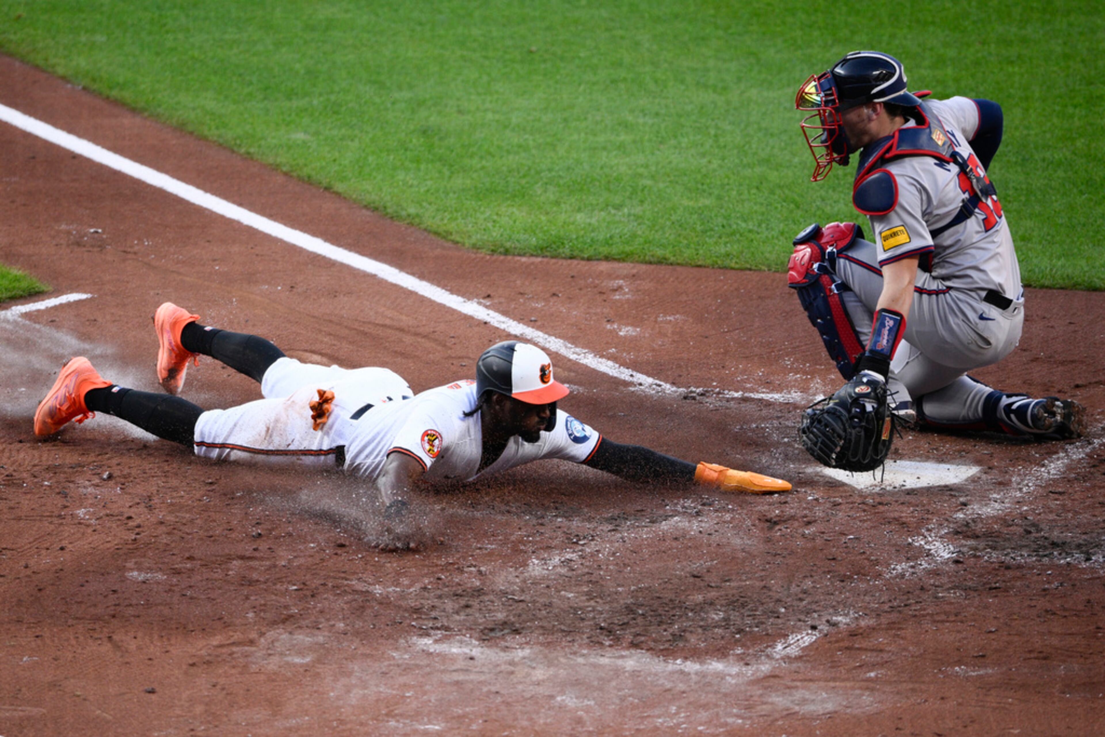 Baltimore Orioles' Jorge Mateo slides home to score Atlanta Braves catcher Sean Murphy, right, during the third inning of a baseball game, Wednesday, June 12, 2024, in Baltimore. (AP Photo/Nick Wass)