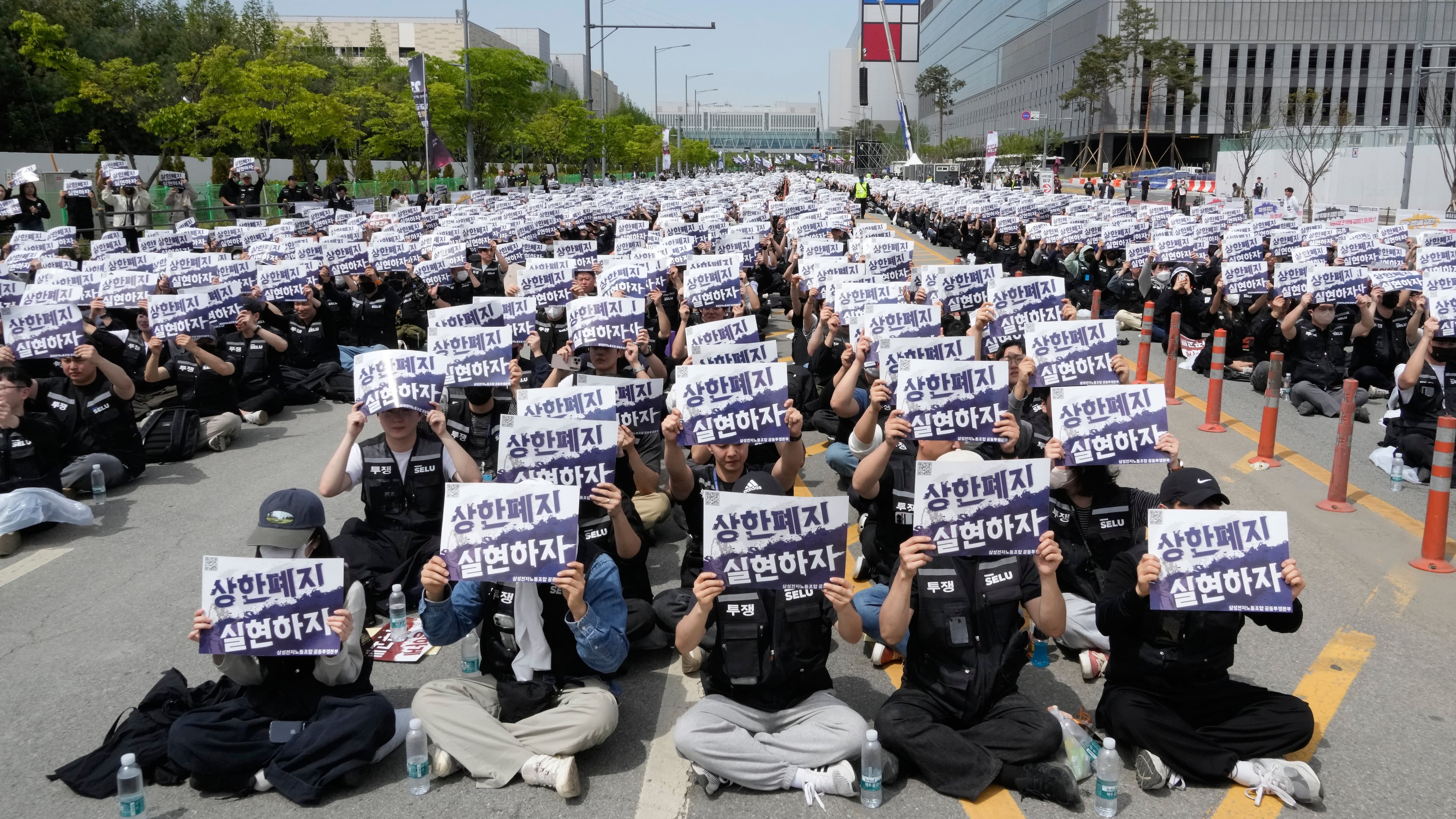 Members of the Samsung Electronics labor union hold up their cards during a rally demanding higher bonuses at its computer chip complex in Pyeongtaek, South Korea, Thursday, April 23, 2026. The letters read "Remove the bonuses caps." (AP Photo/Ahn Young-joon)