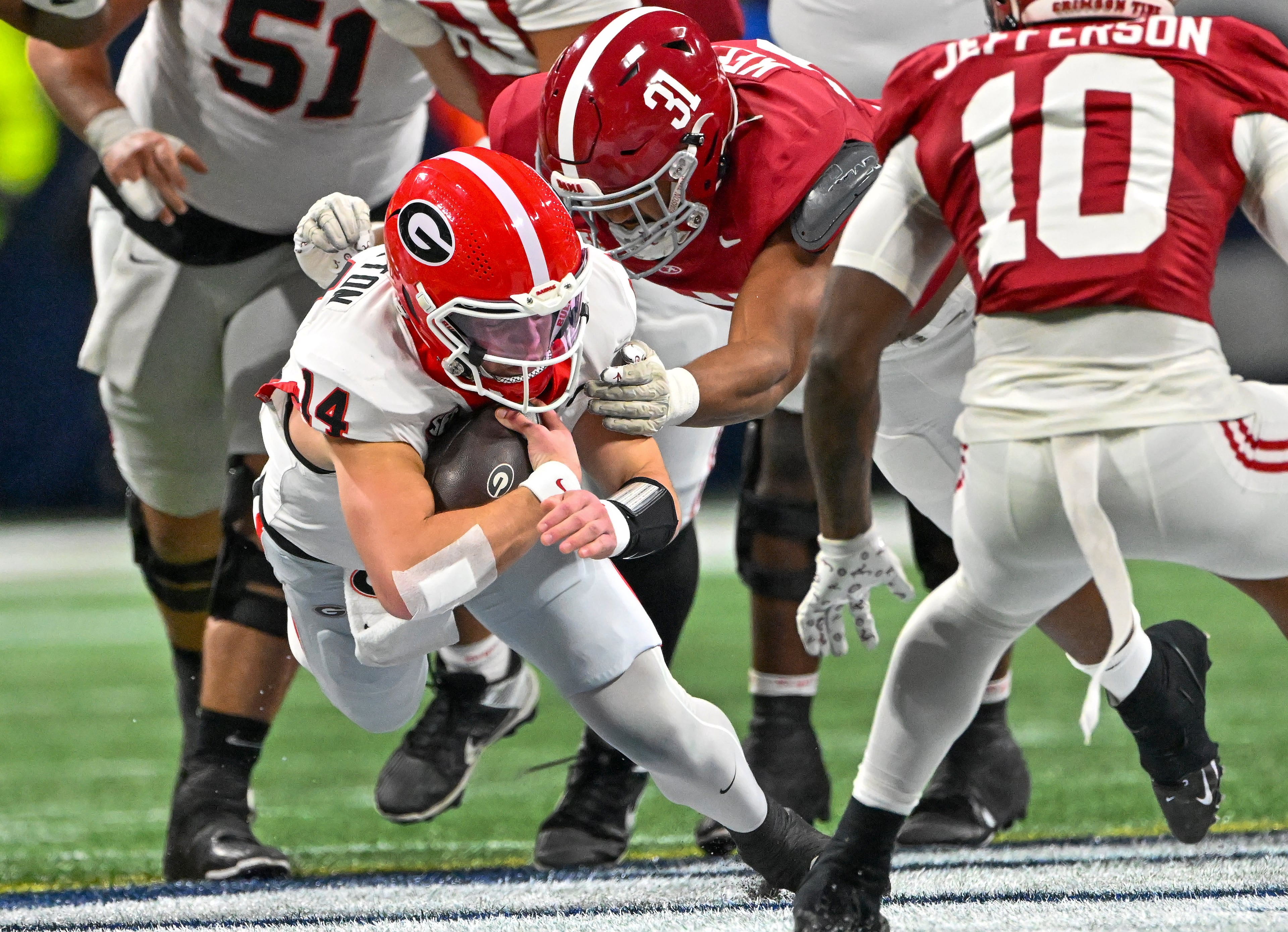 Georgia quarterback Gunner Stockton (14) drives for extra yardage on a keeper play against Alabama defensive lineman Keon Keeley (31) during the first half of the SEC Championship game at Mercedes-Benz Stadium, Saturday, Dec. 6, 2025, in Atlanta. (Hyosub Shin / AJC)