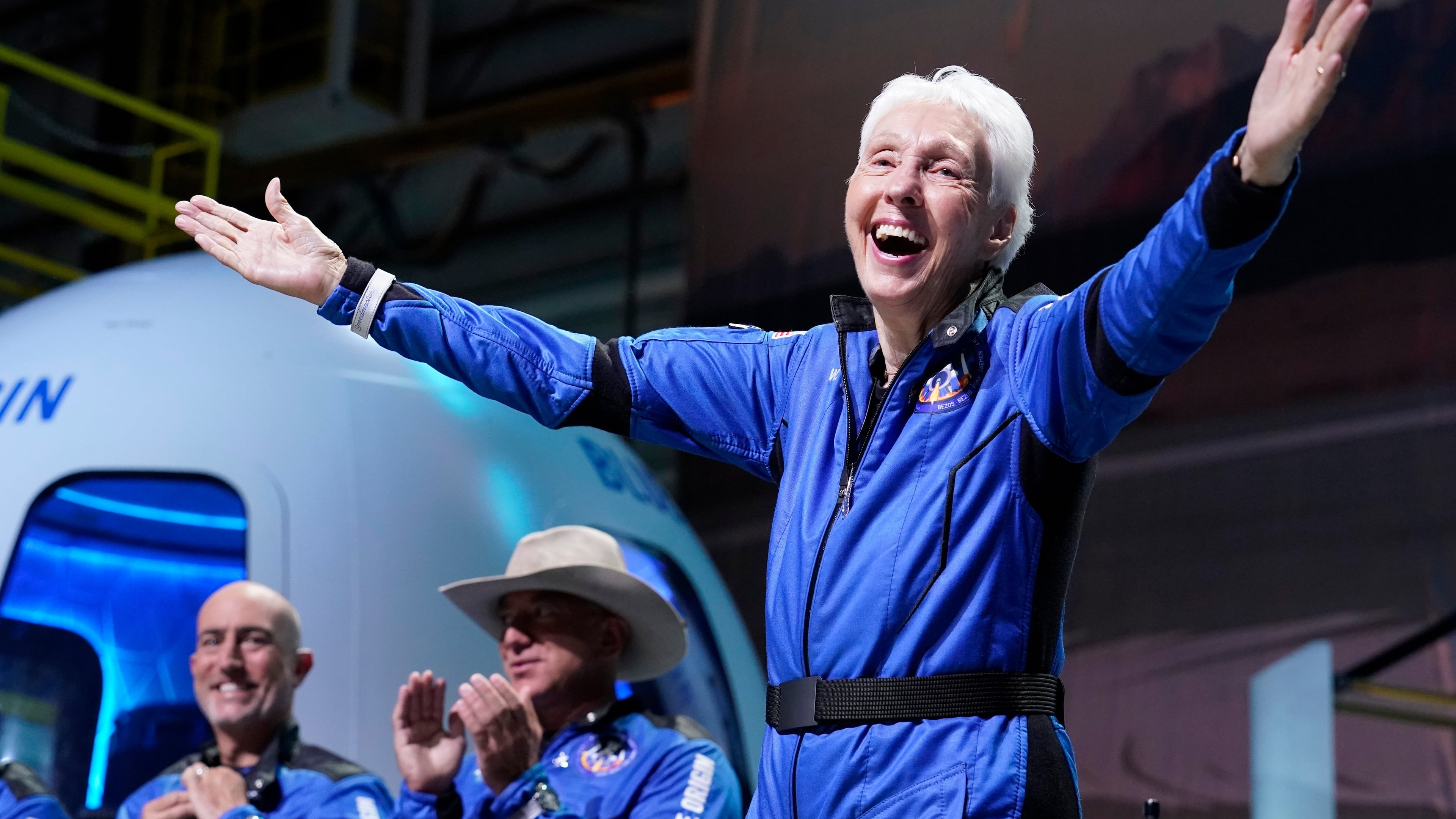 FILE - Wally Funk, right, describes her flight experience as Mark Bezos, left, and Jeff Bezos, left, center, applaud in the spaceport near Van Horn, Texas, July 20, 2021. (AP Photo/Tony Gutierrez, File)