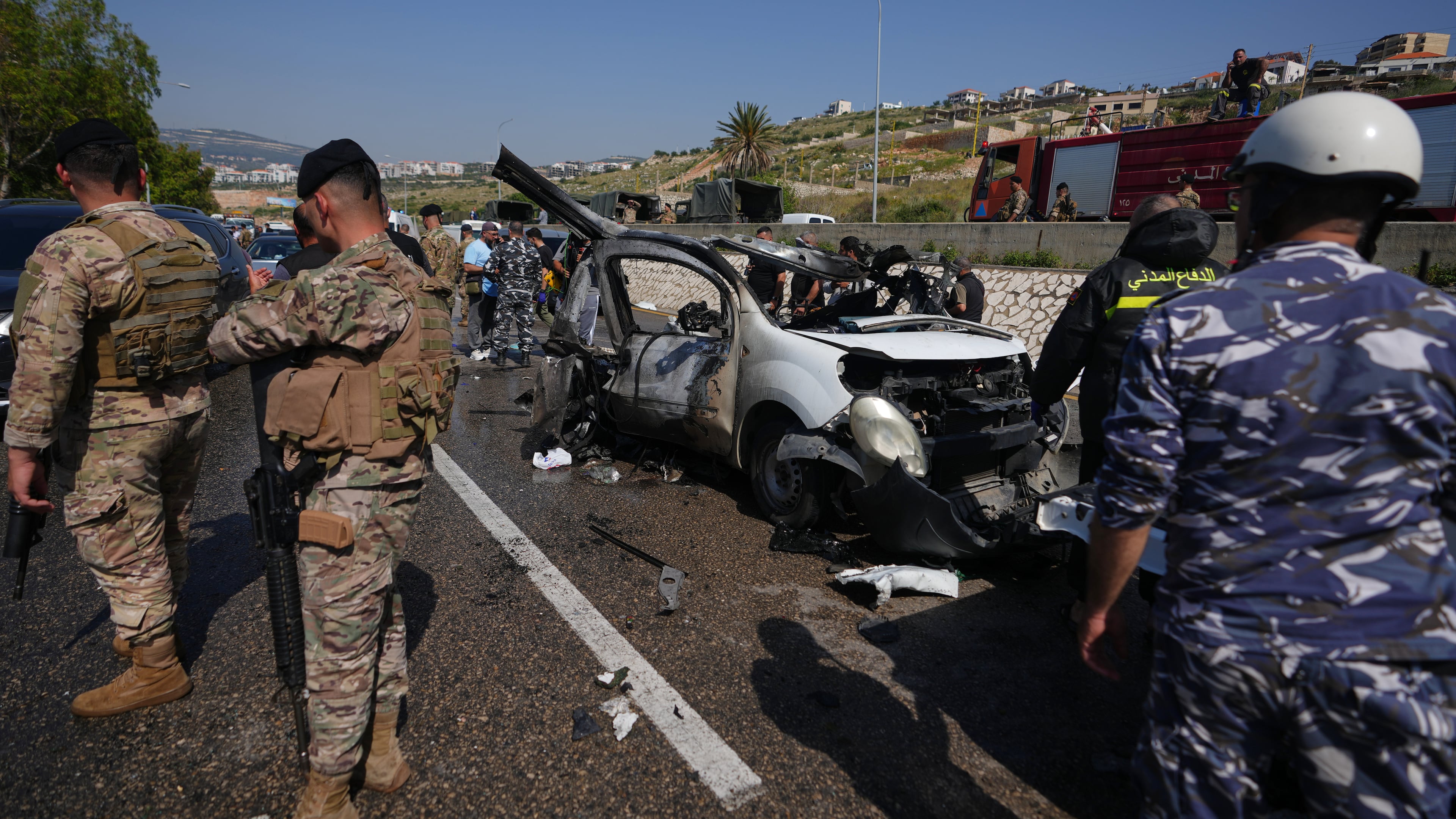 Security forces and emergency responders gather around a damaged vehicle at the scene of an Israeli airstrike that hit a car in the coastal town of Saadiyat, south of Beirut, Lebanon, Saturday, May 9, 2026. (AP Photo/Hassan Ammar)