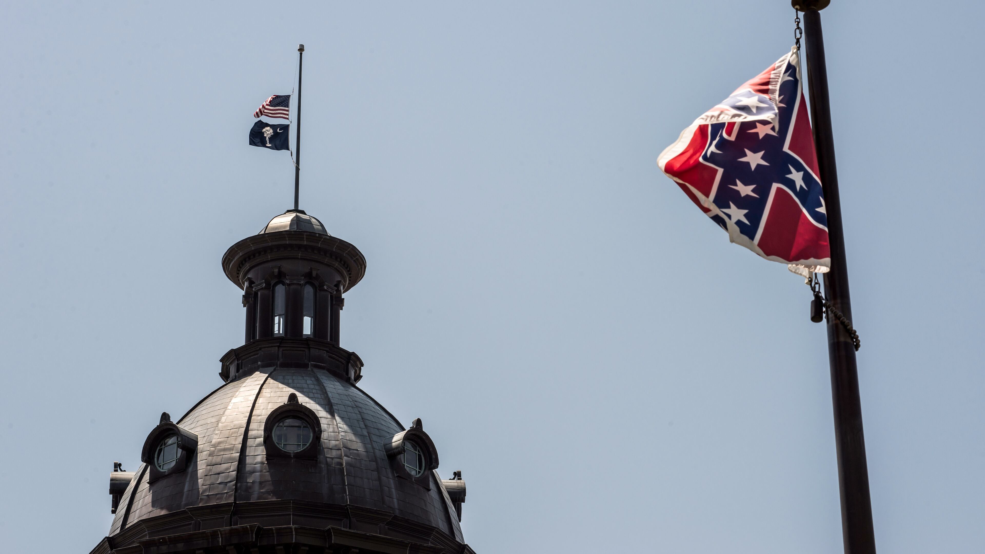 The South Carolina and American flags fly at half-mast as the Confederate flag unfurls below at the Confederate monument June 18, 2015 in Columbia, S.C. Sean Rayford/Getty Images