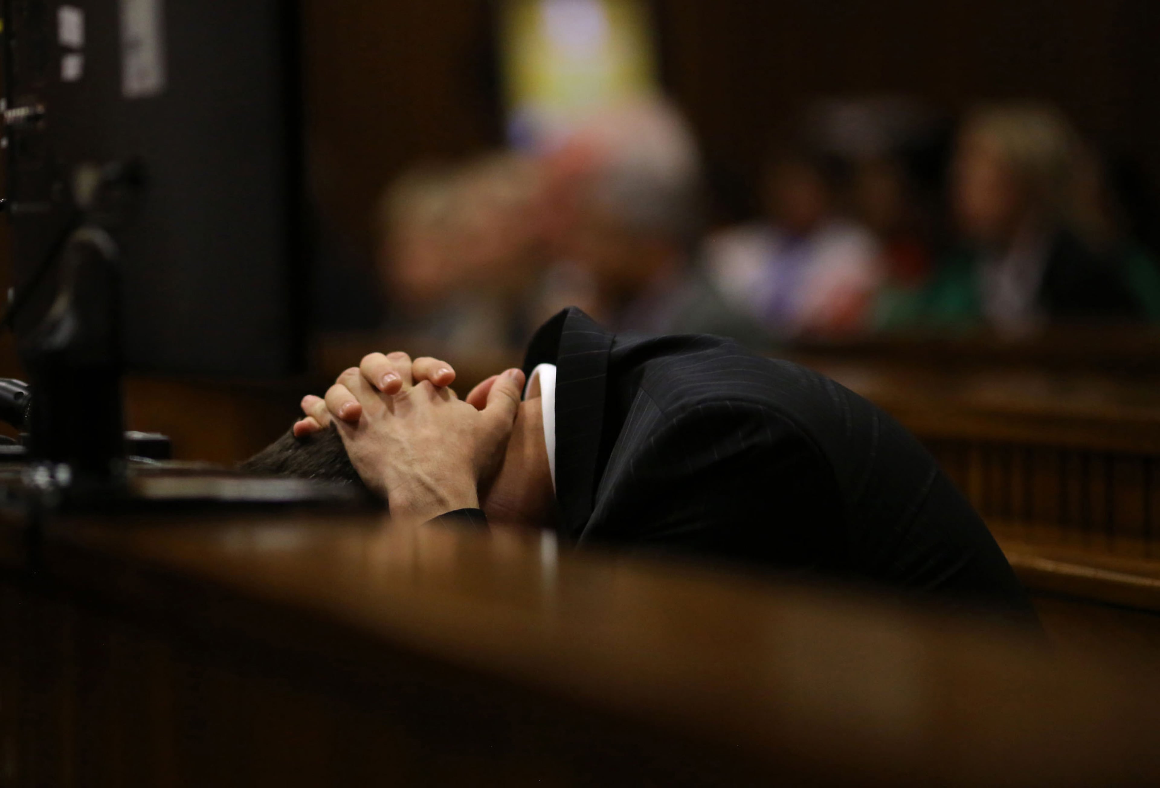 Oscar Pistorius covers his head as he listens to cross questioning about the events surrounding the shooting death of his girlfriend Reeva Steenkamp, in court during his trial in Pretoria, South Africa, Monday, March 10, 2014. Pistorius is charged with the shooting death of his girlfriend Steenkamp in 2013. (AP Photo/Siphiwe Sibeko, Pool)