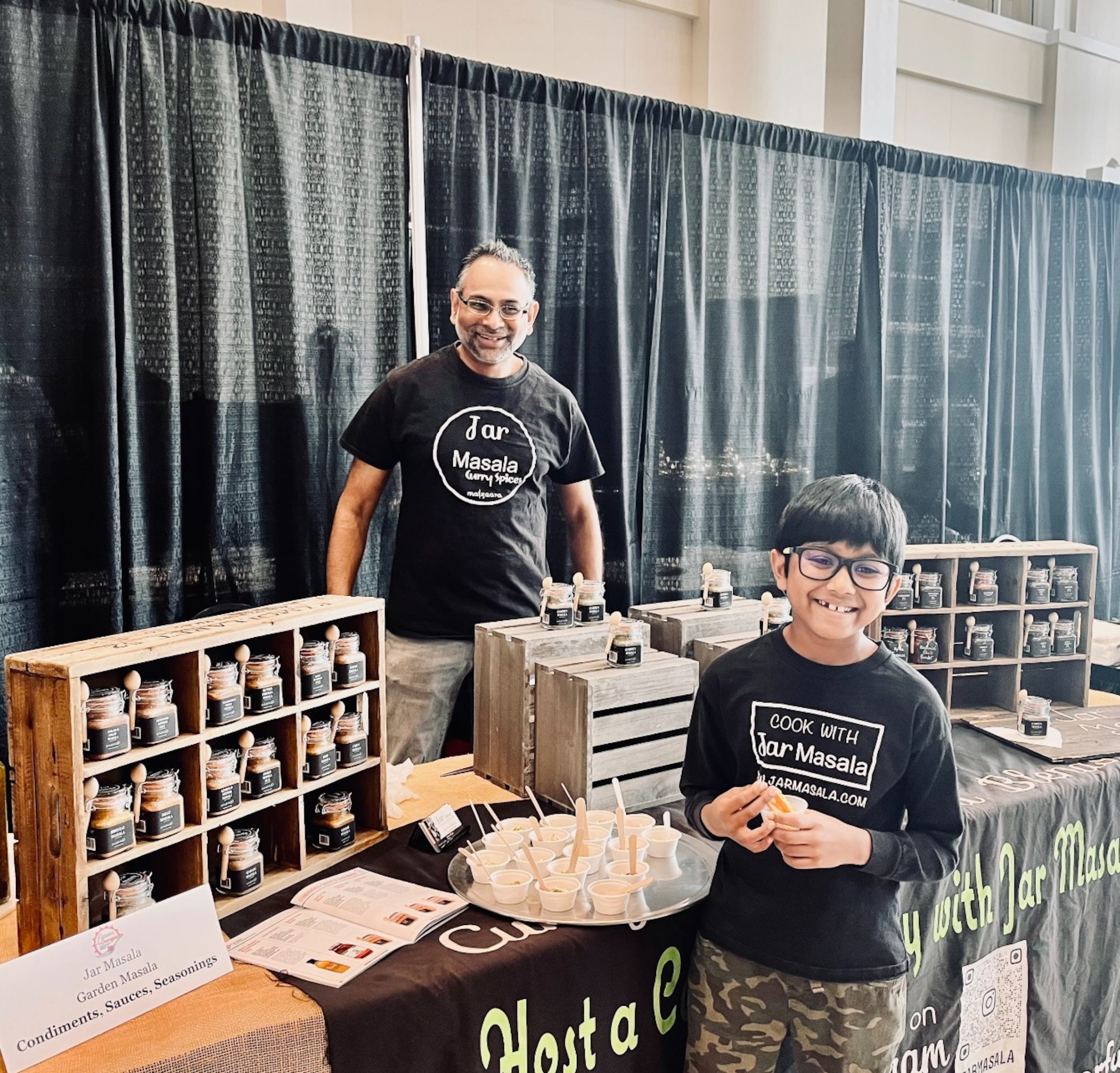 Dad Likhon and son Rahil — the family’s official food taster — help promote Lipi Begum’s Jar Masala at the 2025 Flavor of Georgia competition. (Courtesy of Jar Masala)
