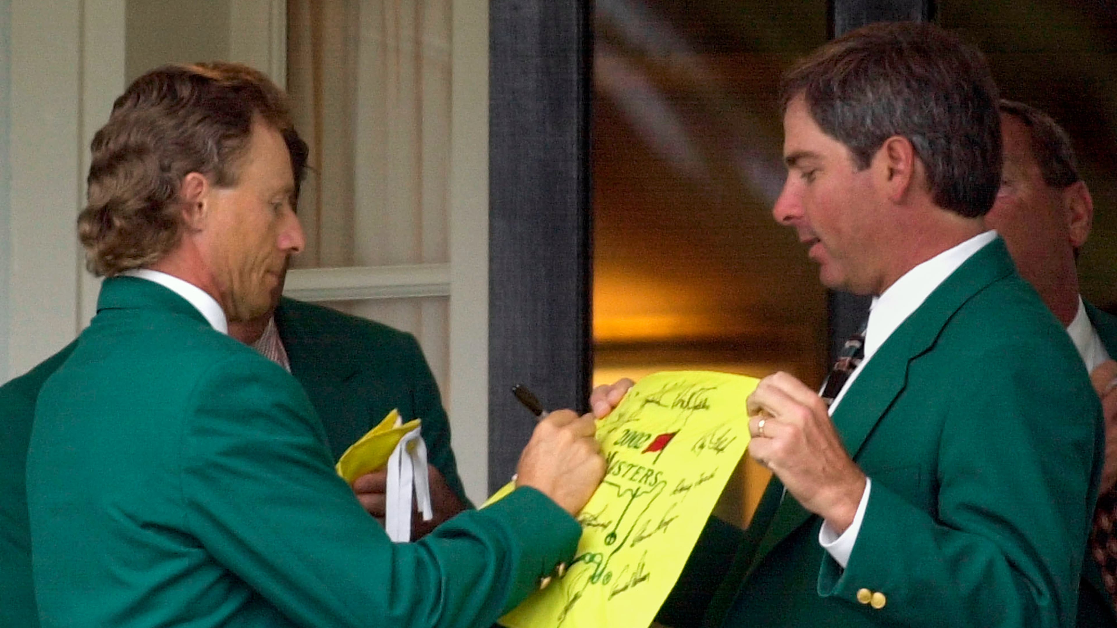 FILE - Former two-time Masters Champion Bernhard Langer, left, signs an autograph for fellow former champion Fred Couples, right, at the Augusta National Golf Club prior to the annual Champions dinner at the 2002 Masters, April 9, 2002, in Augusta, Ga. (AP Photo/Dave Martin, File)