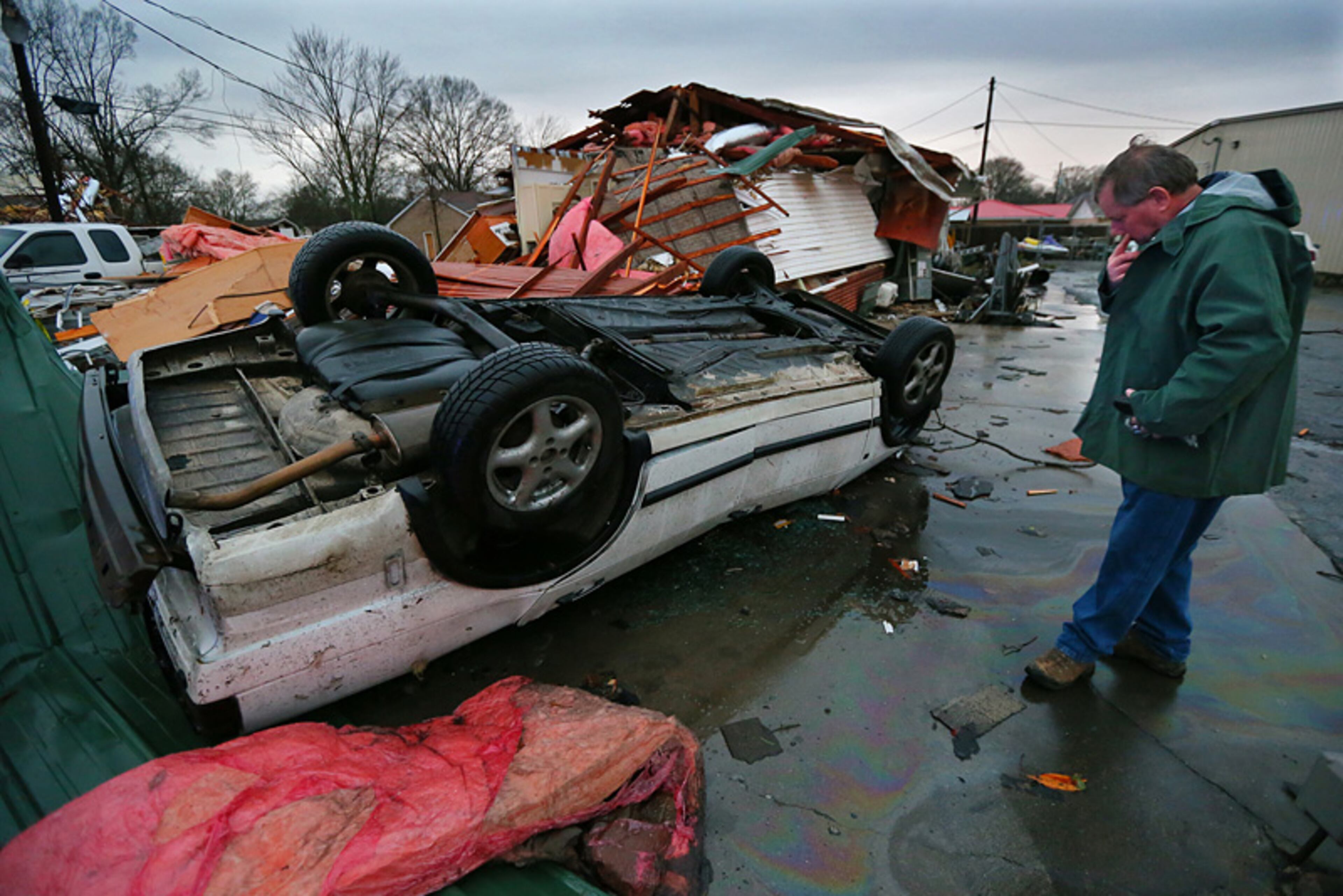 Kevin Fleming looks over his destroyed car and Fleming Electric Services business in Adairsville following a tornado on Wednesday. Fleming said he had just parked and entered the business when the tornado hit. He took shelter in the bathroom inside the business and said the storm hit without warning.