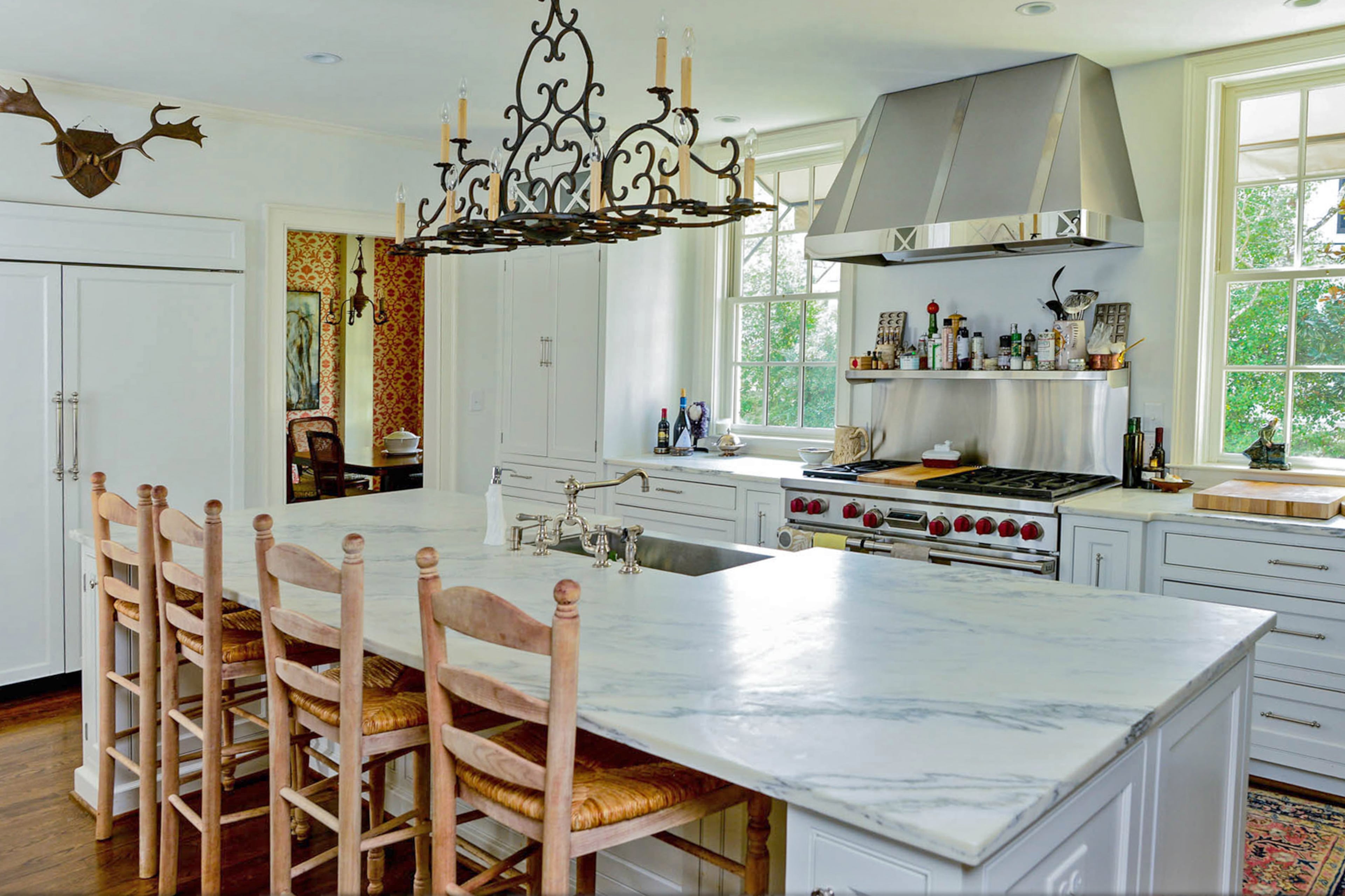 An island topped with Carrara marble is the center of Dina Woodruff's kitchen. A traditional bar light, from Solaria in Decatur, hangs above. The kitchen also was renovated by the previous owners with features such as the Wolf range while other appliances are hidden.