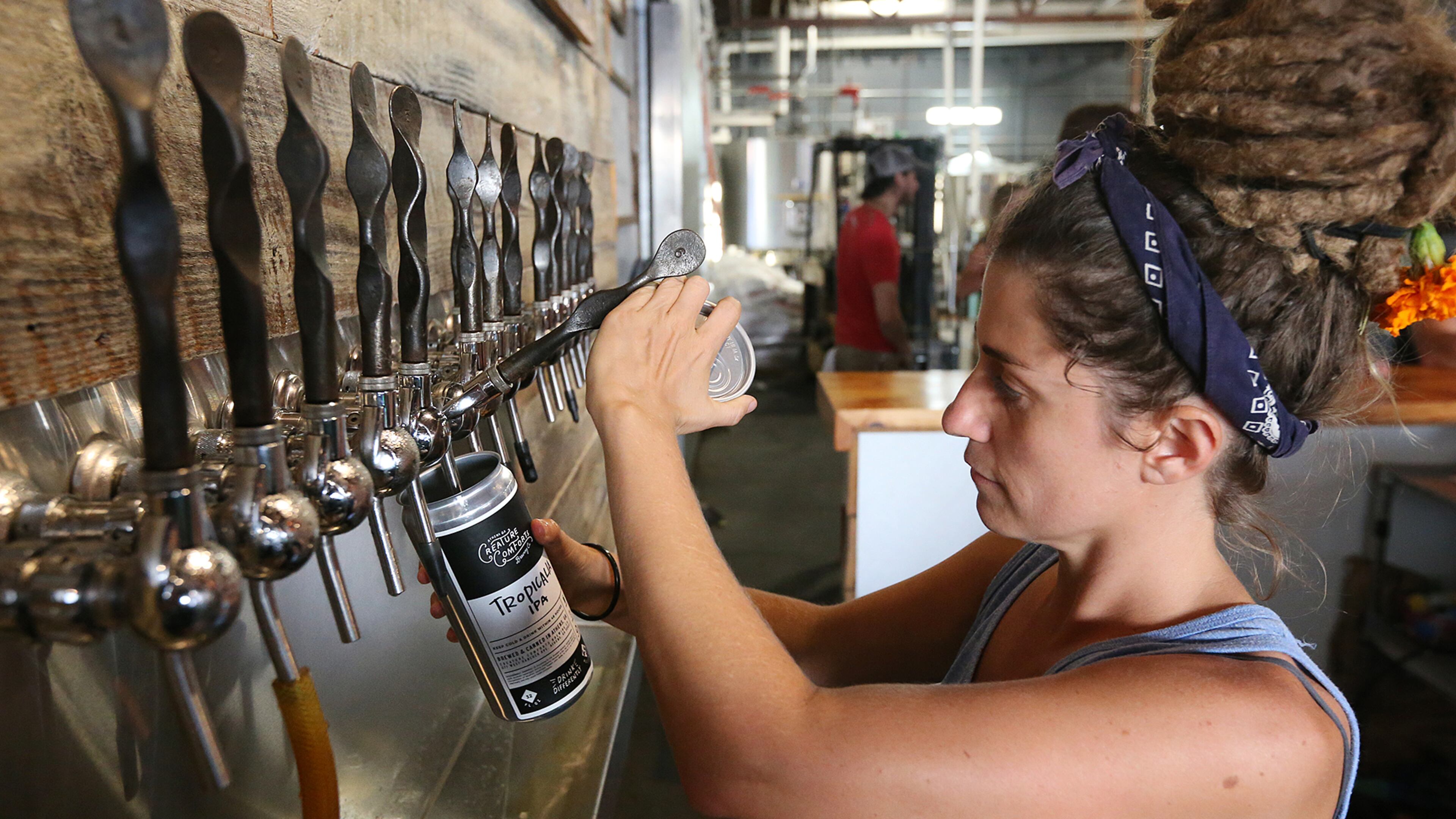 A Creature Comforts Brewing Company employee fills a 32-oz. crowler for a customer to take home Aug. 27 in Athens. (AJC Photo / Curtis Compton)