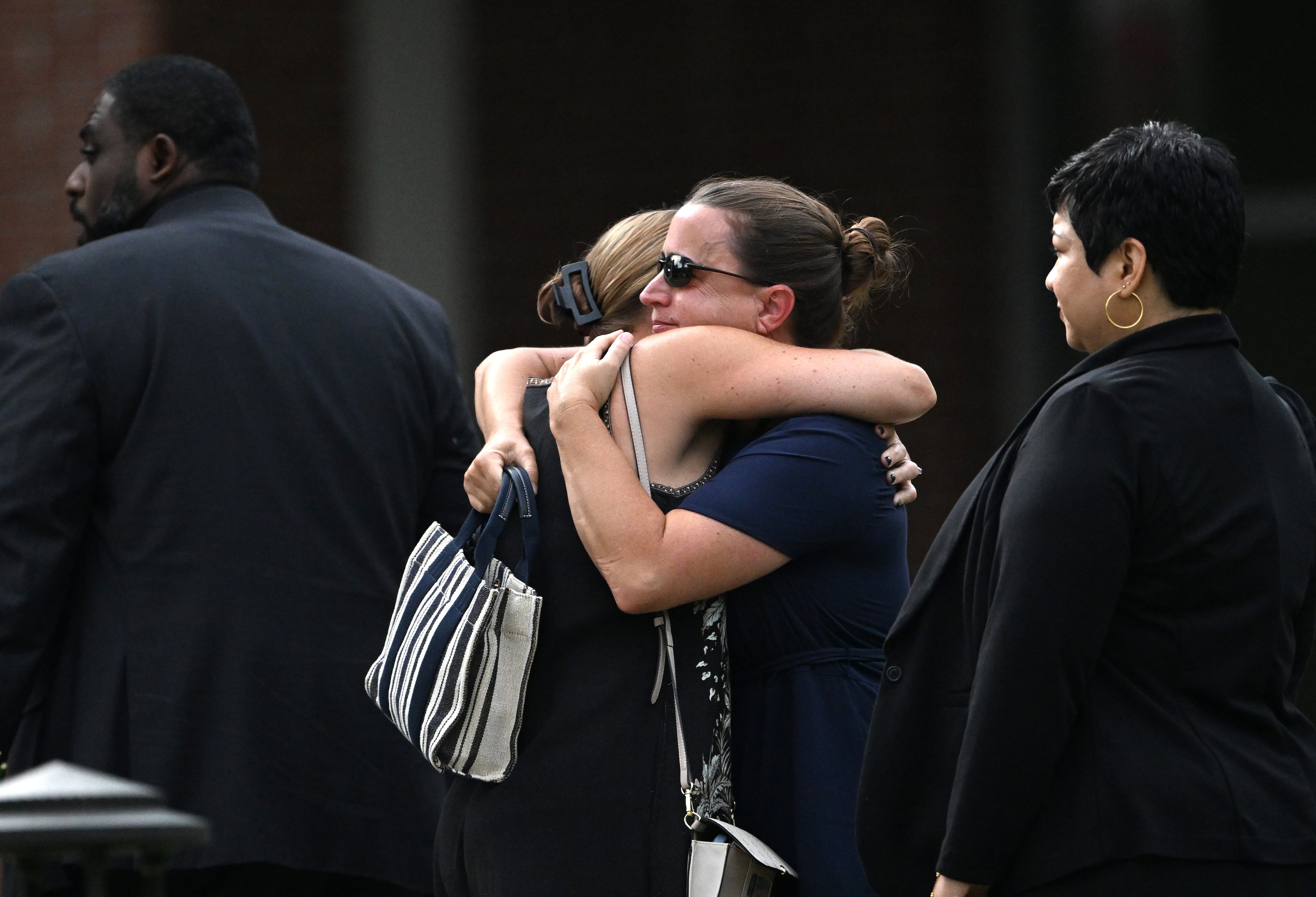 Mourners embrace before the memorial service for DeKalb County police Officer David Rose, who was killed while responding to the Aug. 8 shooting at the CDC. (Hyosub Shin/AJC)