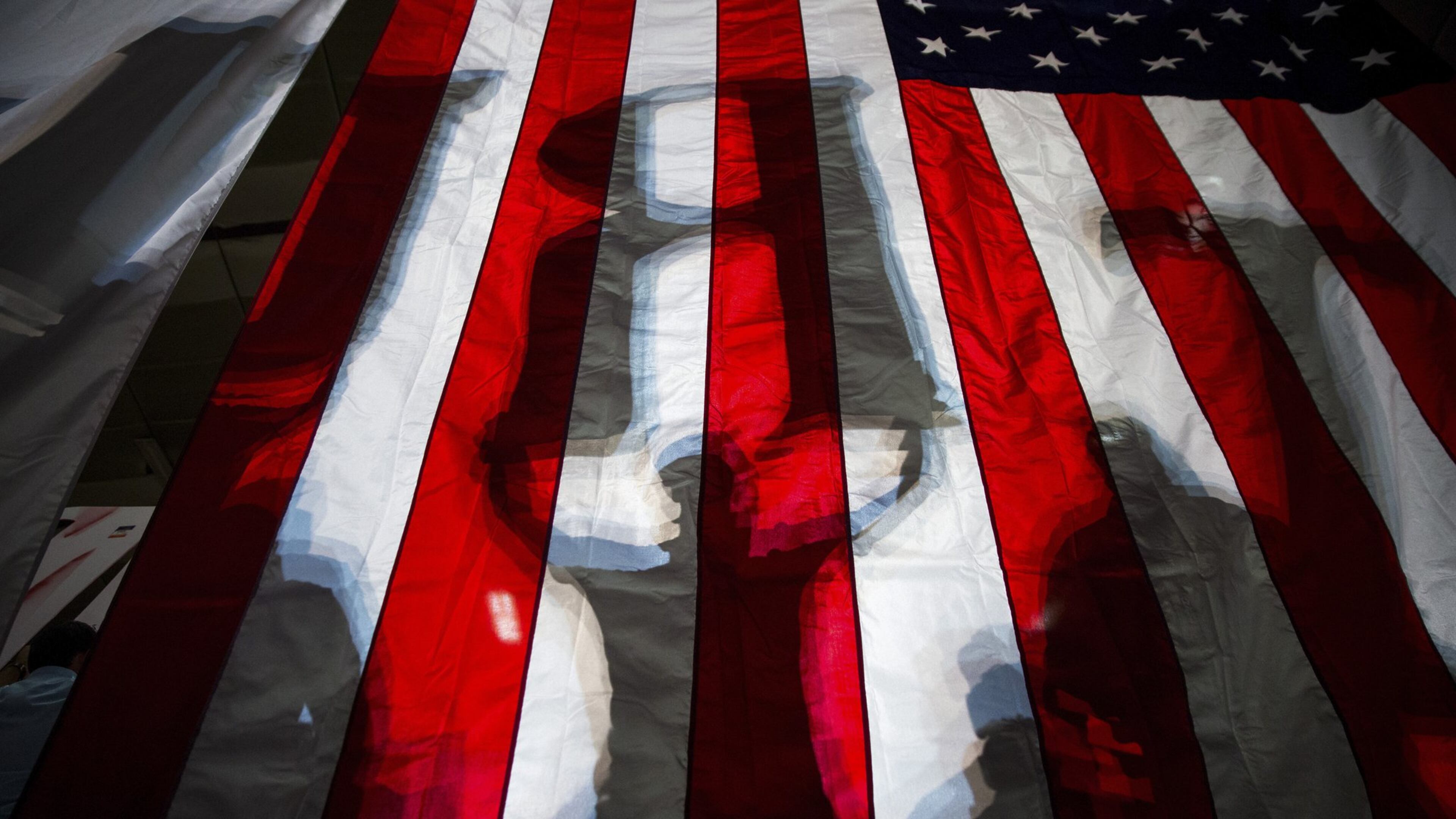 Shadows of Donald Trump supporters, holding up letters to spell his name, show through an American flag at a campaign event for the Republican presidential nominee, at the Travis County Exposition Center in Austin, Texas, Aug. 23, 2016. On Thursday, Hillary Clinton plans to delivered a major address denouncing Trump’s embrace of the “alt-right” political philosophy, presenting his choice as an especially ominous turn in a presidential election full of them. (Damon Winter/The New York Times)