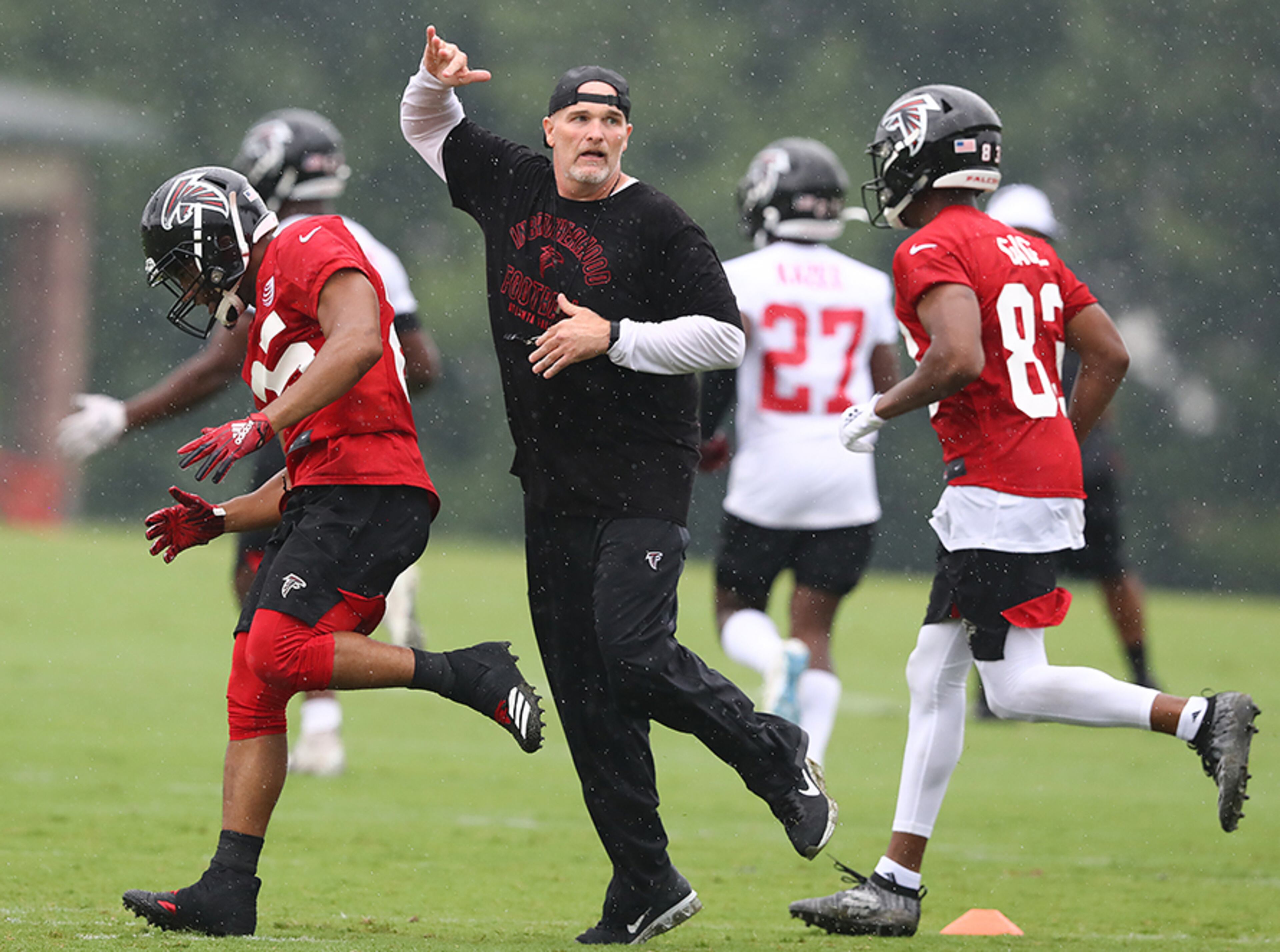 Falcons head coach Dan Quinn and running back Ito Smith narrowly avoid a collision as they hustle from drill to drill during the second practice of training camp Tuesday, July 23, 2019, in Flowery Branch.