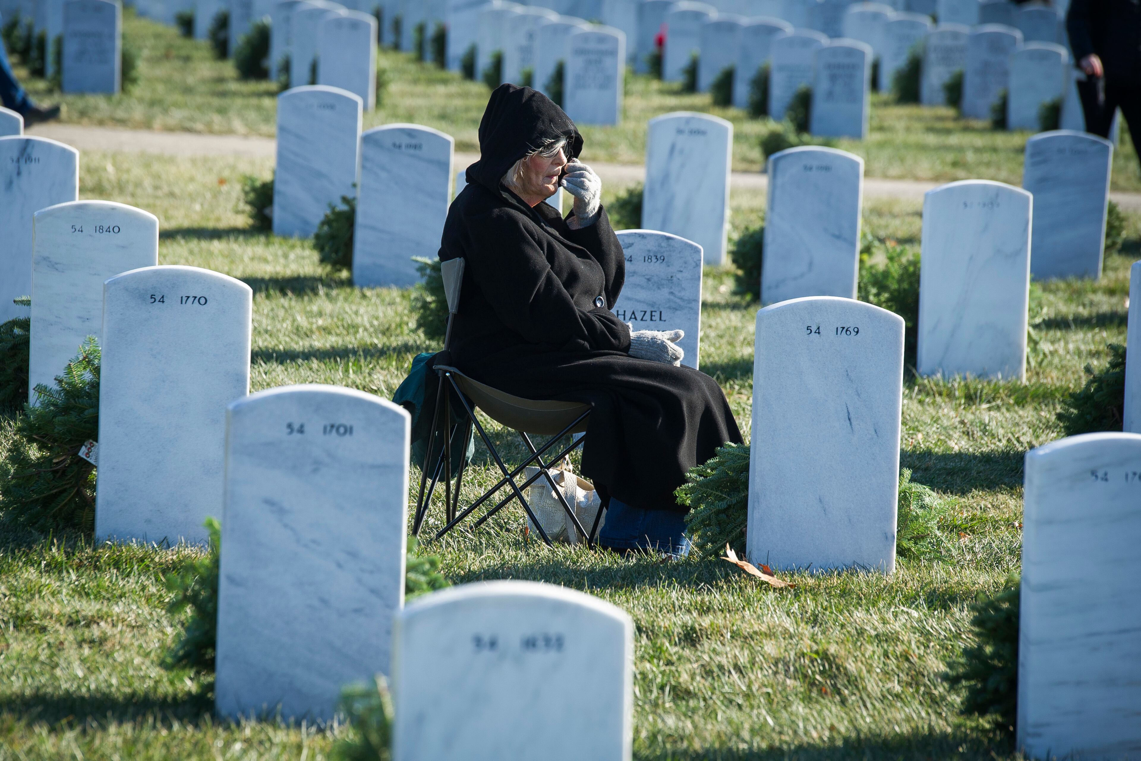 Mattie Ethridge, of Chattanooga, Tenn, sits at the grave of her husband, Air Force Major Walter Ethridge, a Vietnam War veteran, at Arlington National Cemetery as Wreaths Across America places remembrance wreaths on headstones at the cemetery in Arlington, Va., Saturday, Dec. 16, 2017. (AP Photo/Cliff Owen)