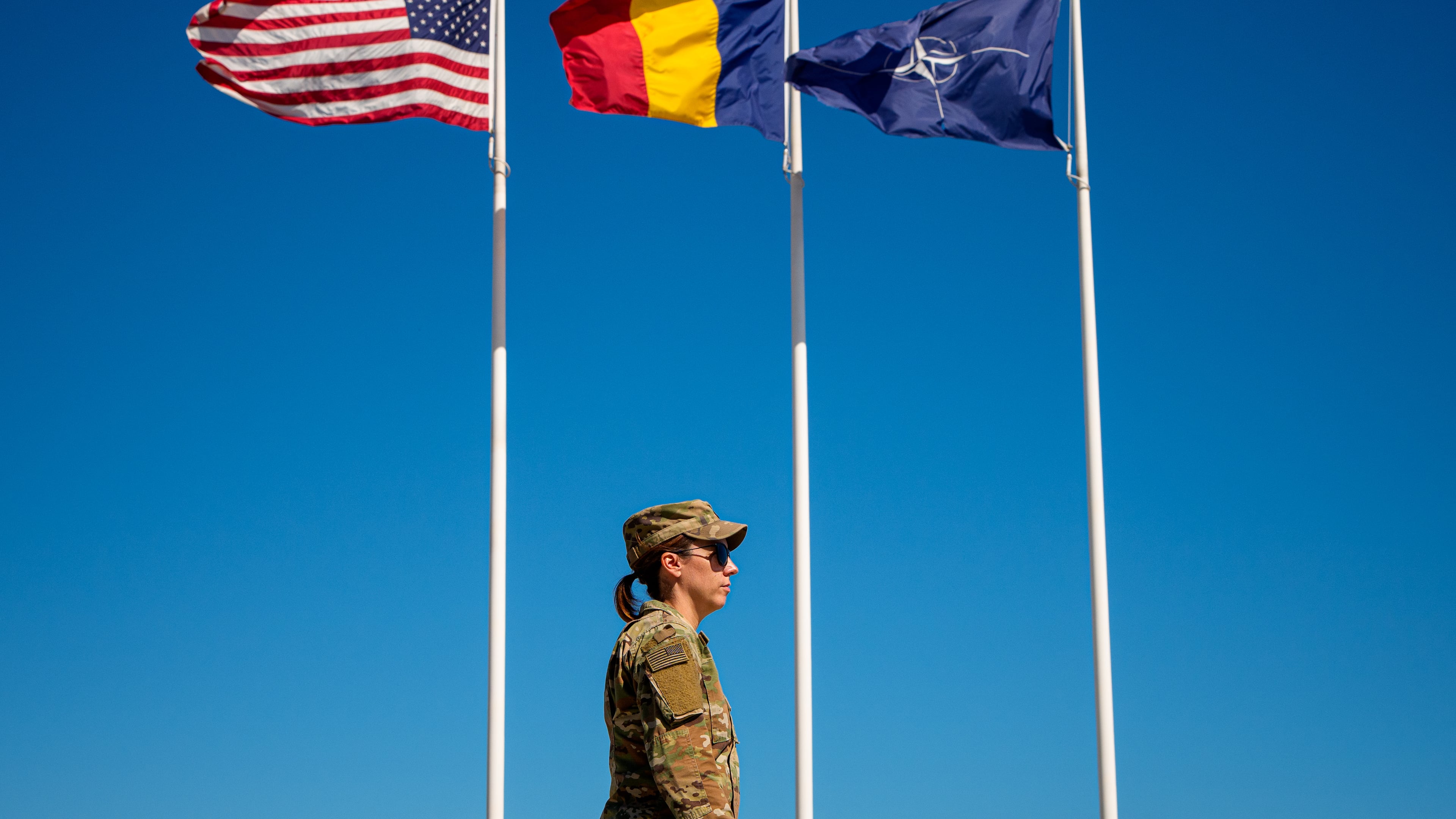 U.S. Staff Sergeant Alyssa Blom walks by flags at the Mihail Kogalniceanu Air Base, in Mihail Kogalniceanu, Romania, Thursday, Sept. 10, 2026. (AP Photo/Andreea Alexandru)